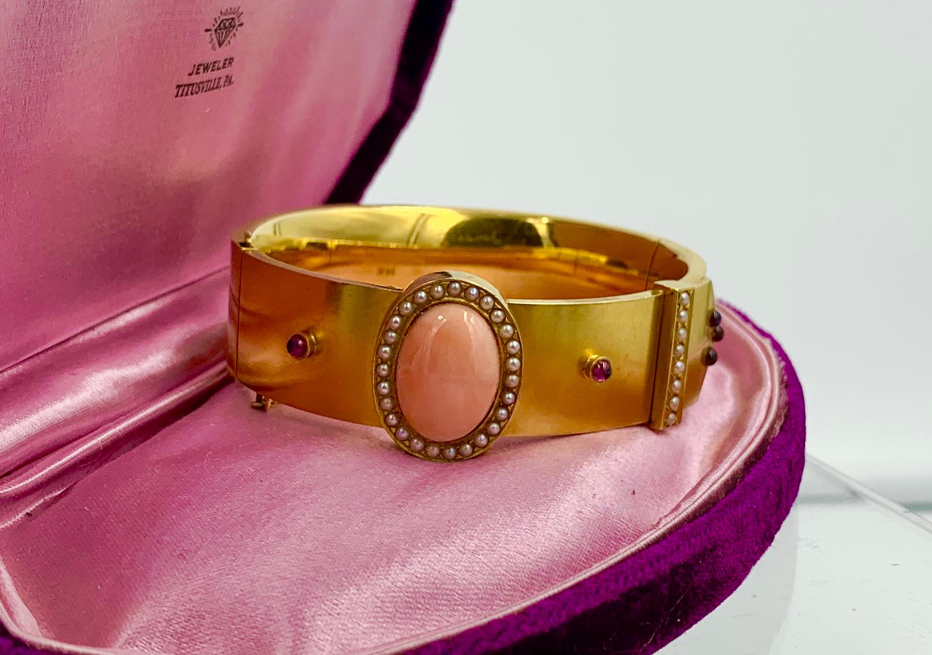 A spectacular Victorian Bangle Bracelet in 14 Karat Gold in a Buckle motif with a stunning central Salmon Coral cabochon with Seed Pearl and Bohemian Garnet accents.  The Coral is a perfect pink salmon color.  It is an oval cabochon of 17mm tall and