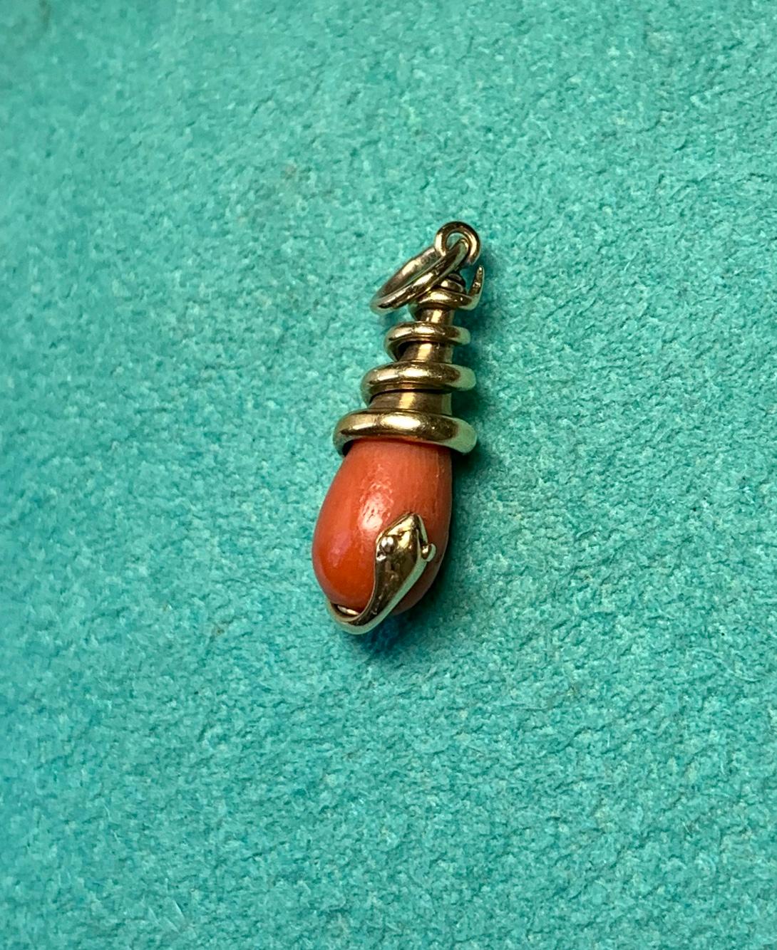 A rare antique Victorian Coral Snake Pendant depicting a snake or serpent wrapped around a gorgeous natural coral pendant.  The snake in 14 Karat gold with wonderful details throughout the head with its eyes and open mouth.  The snake pendant has