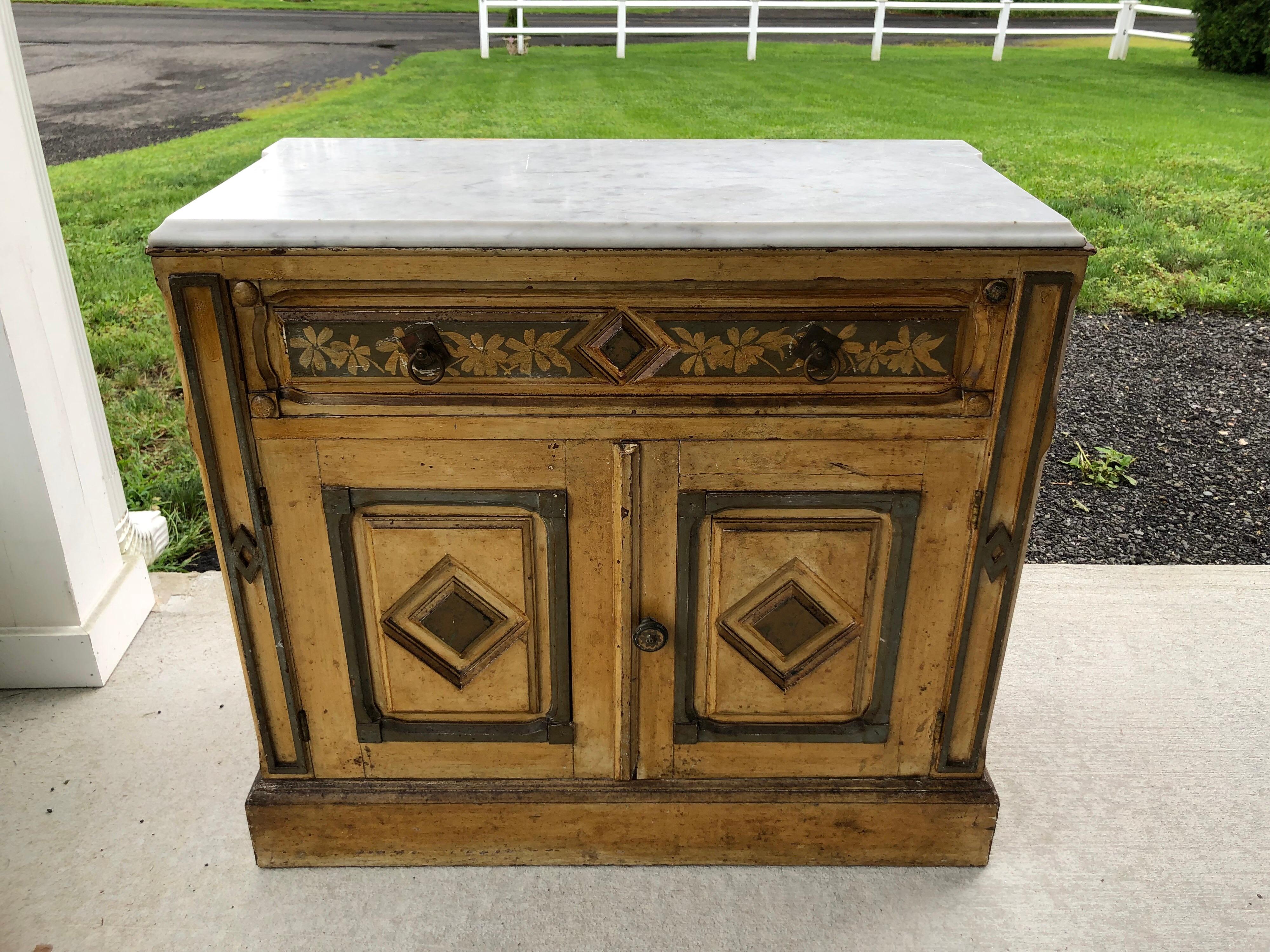 Victorian cottage style hand-painted marble top dresser. This sweet dresser would complement any country farmhouse or cottage. Hand-painted panels grace this lovely Victorian era piece that is topped with a loose white marble with beveled edges. Two