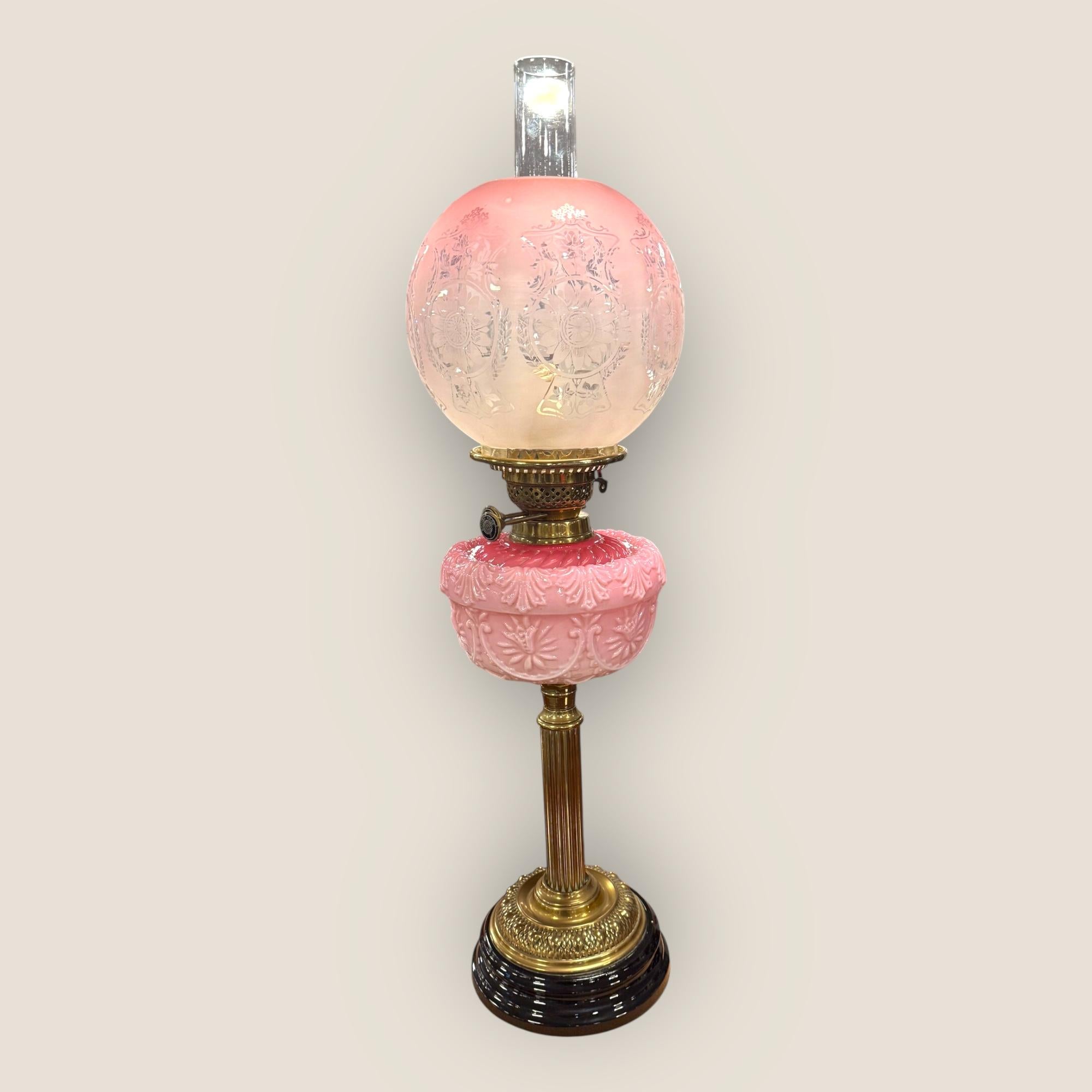 Nous avons ici une lampe à huile victorienne ancienne en verre gravé Cranberry avec colonne et base en laiton. Le magnifique abat-jour gravé de couleur canneberge est entouré de scènes florales et comporte également une police de