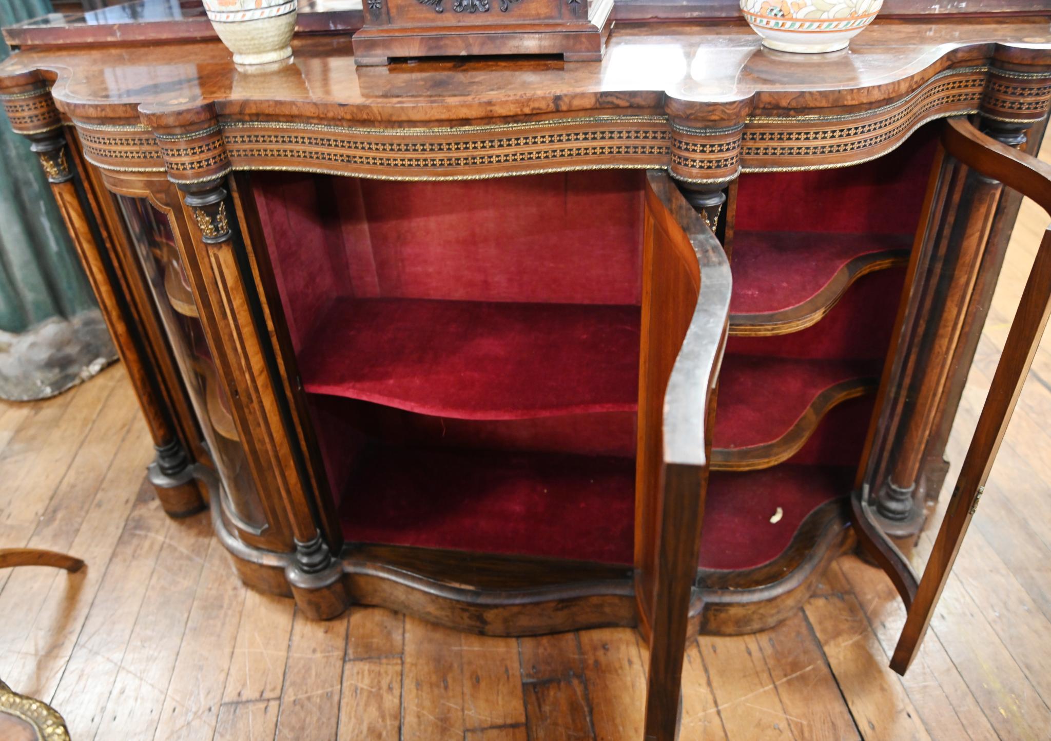You are viewing a gorgeous Victorian serpentine credenza walnut
Numerous wood inlays embedded into the walnut of the main structure
Circa 1860 on this period Victorian antique
Ormolu fixtures are also original to piece
Glass doors to either side