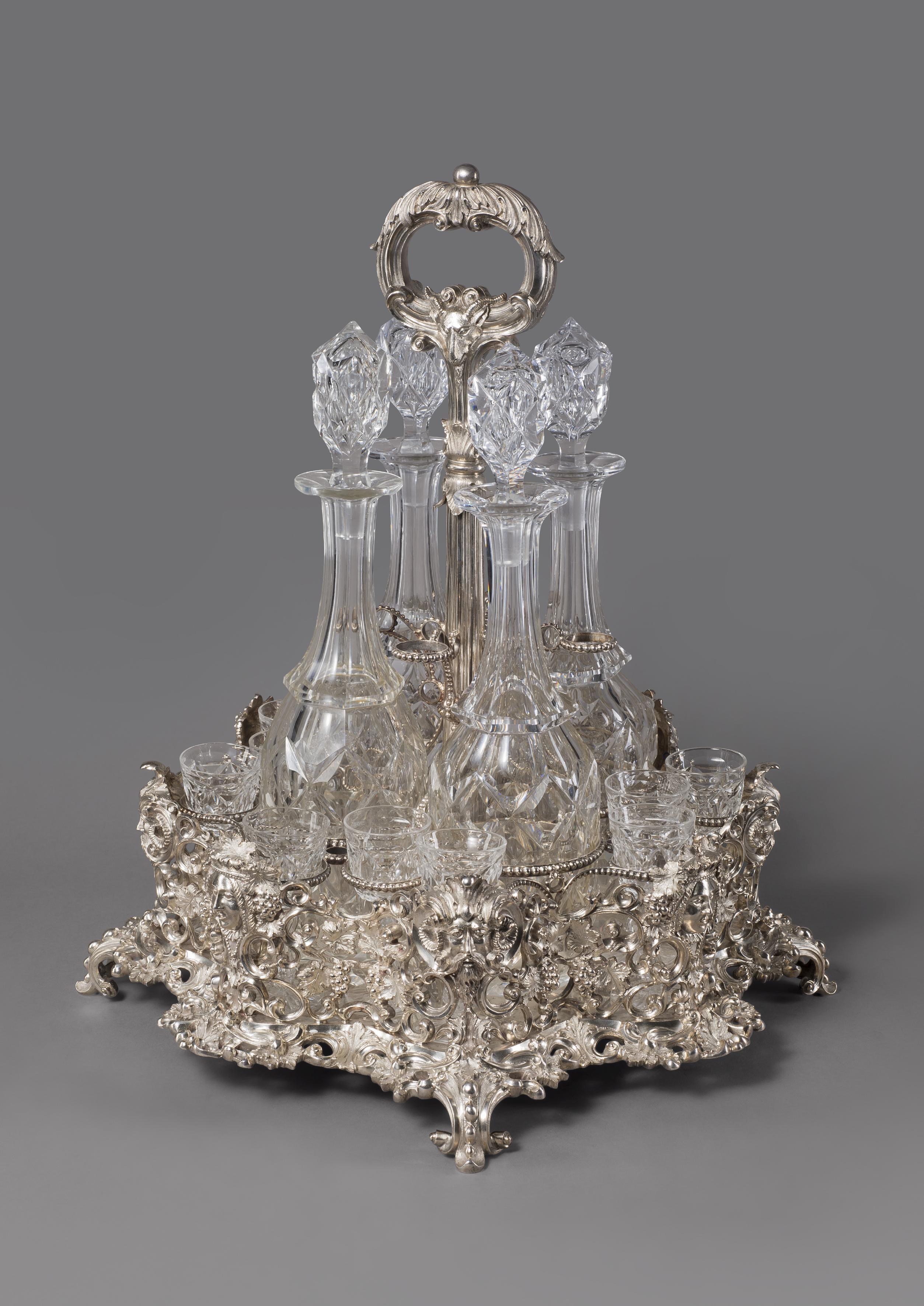A large Victorian silver and cut-glass liqueur set, probably by John James Keith.

London, 1860.

The base boldly cast and pierced with bacchanal masks between fruiting vines and foliate scrolls, the beaded frame and central shaft terminating
