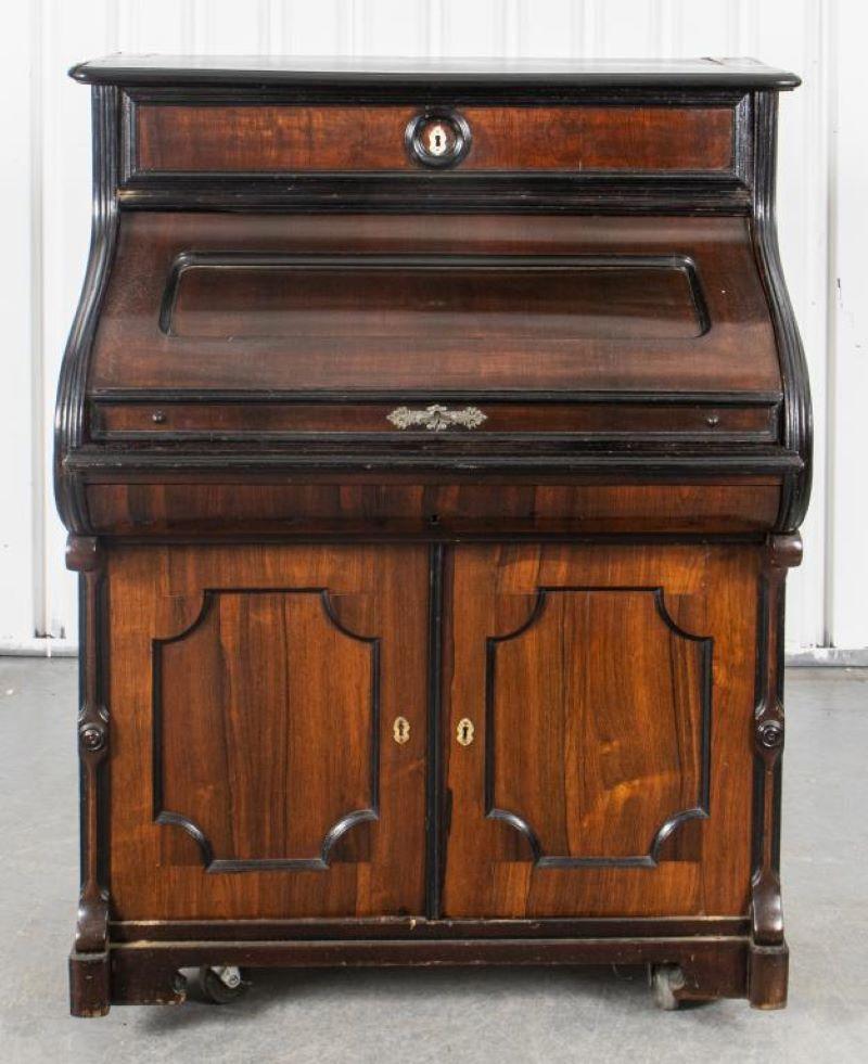 Victorian cylinder secretary cabinet in carved and parcel ebonized wood with mother of pearl keyhole covers and drawer pulls. 47.5