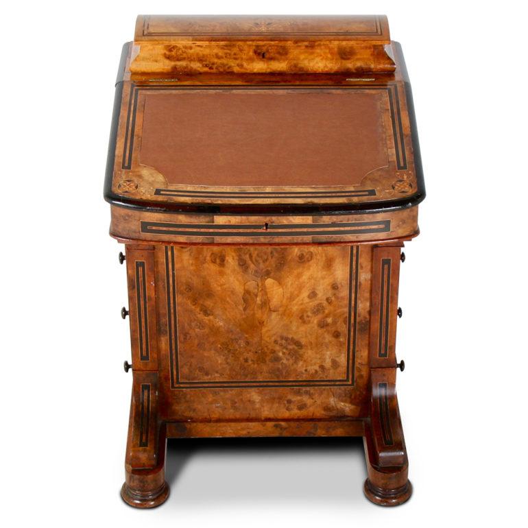 An English figured walnut ‘Davenport’ desk fitted with four graduated drawers to one side with opposing false drawers, the leather top opening to reveal smaller drawers, the top back with further fitted with lidded compartment. Inlaid with