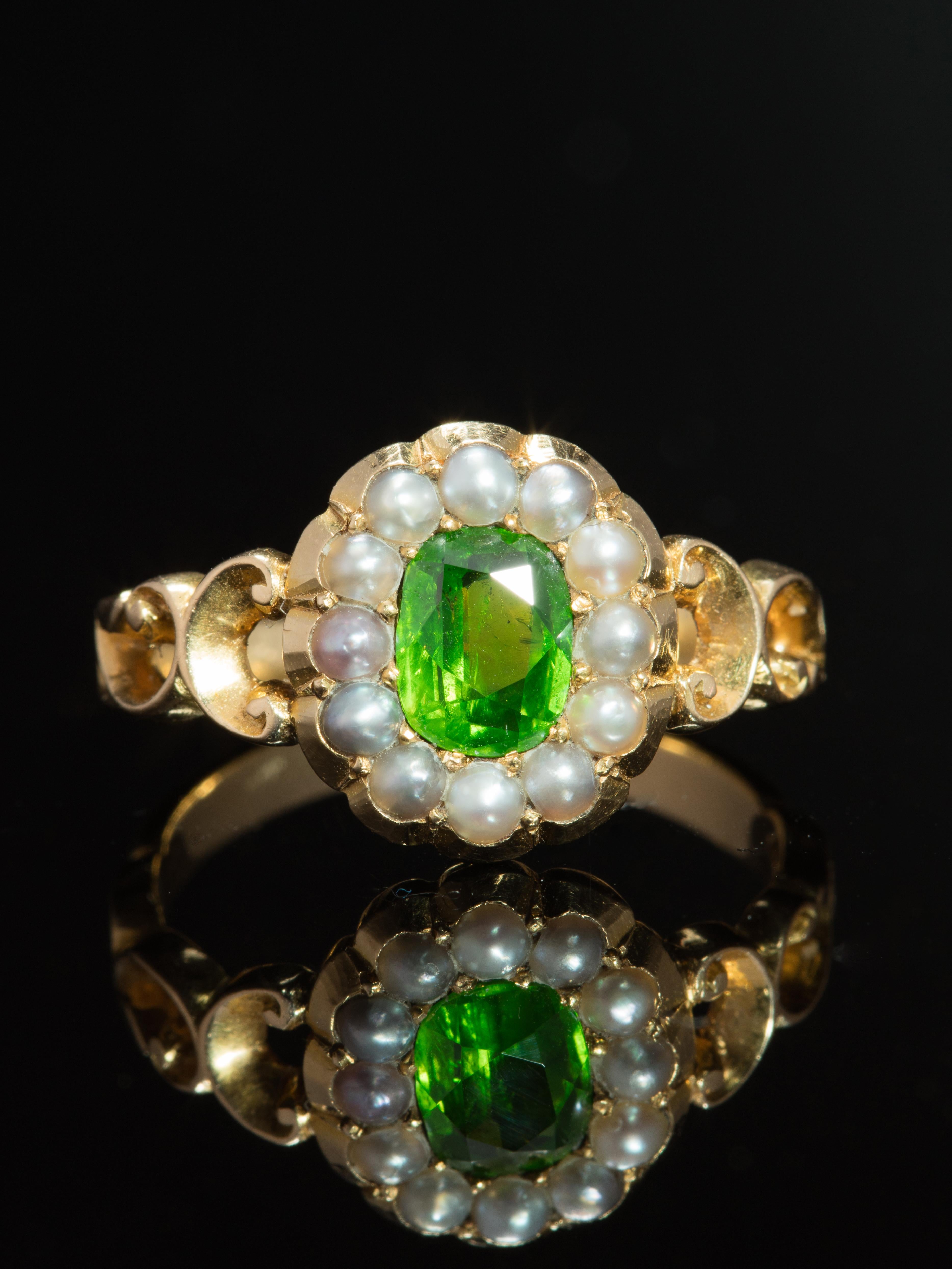 Full of romanticism and symbolism is this dramatic flower ring featuring a vibrant and richly saturated green demantoid garnet complemented by lustrous delicate pearls in a classic cluster design. 

Extremely popular during the late 1800s and early
