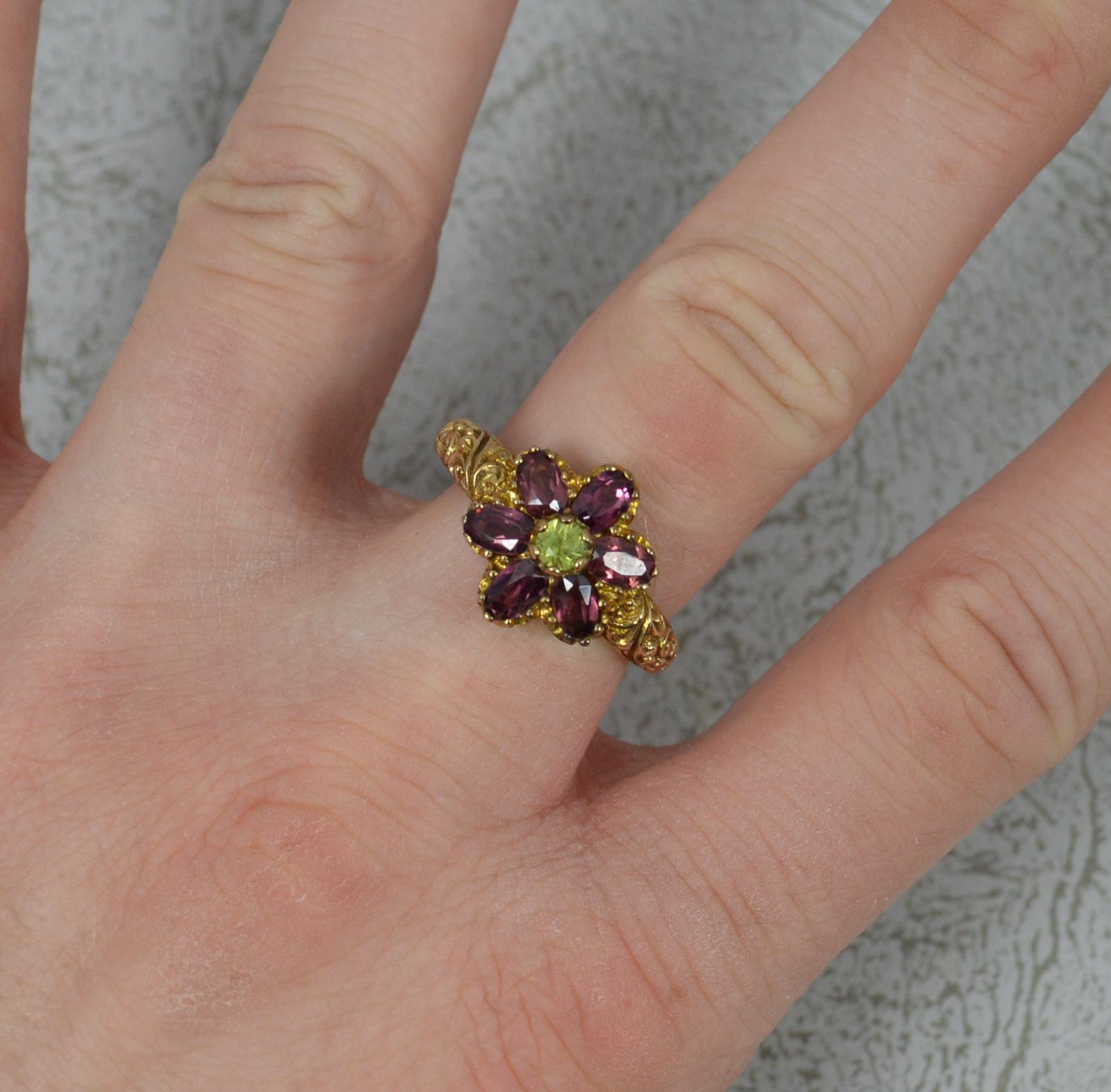 A stylish ladies ring. Victorian design, contemporary piece.
9 carat yellow gold example. Deep floral relief to shoulders.
A round cut peridot to centre with six oval cut garnets surrounding. 
12.5mm x 14mm approx.

Condition ; Excellent. Crisp
