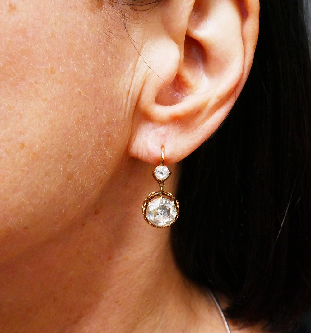 	A delicate pair of Victorian rose cut diamond earrings, made of 14 karat gold.
	The earrings of drop dangling design, each feature two diamonds. The top one is a smaller, four-prong set stone. The dangling larger diamond is seven-prong set in a