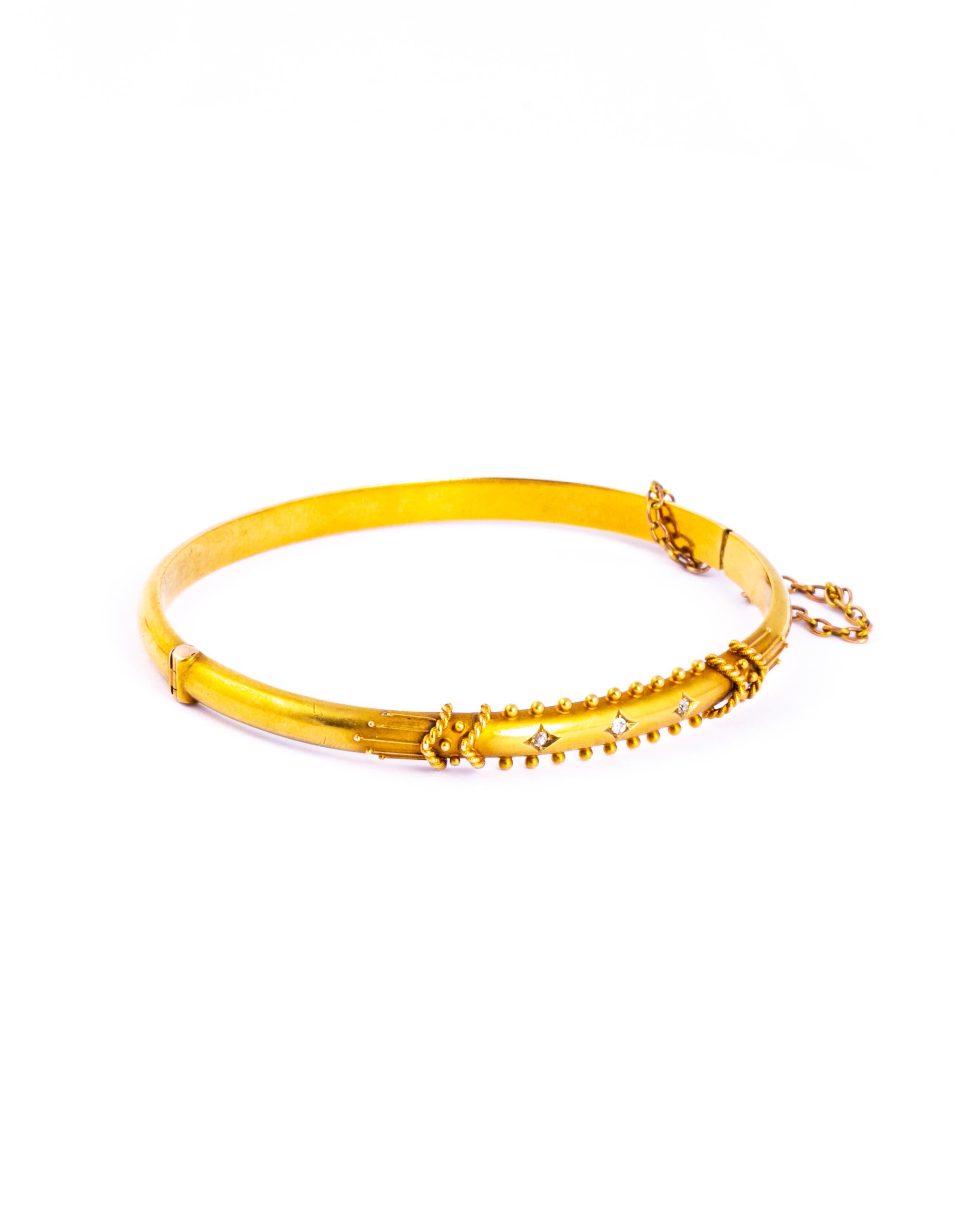 The 15 carat gold is bright and the bangle has so much detail. The central panel holds three round cut diamonds. Either side of the panel is orb detail and two chevron style rope twists either end. The bangle comes in original box. 

Inner Diameter: