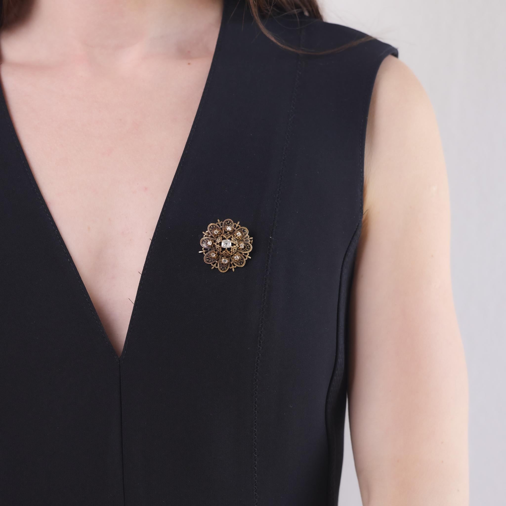 This Victorian brooch from the 1880s is crafted in 18k yellow gold with detailed enamel work and features a center old mine cut diamond weighing approximately 0.45 carats, graded H color and VS1 clarity. It is accented by eight additional old mine