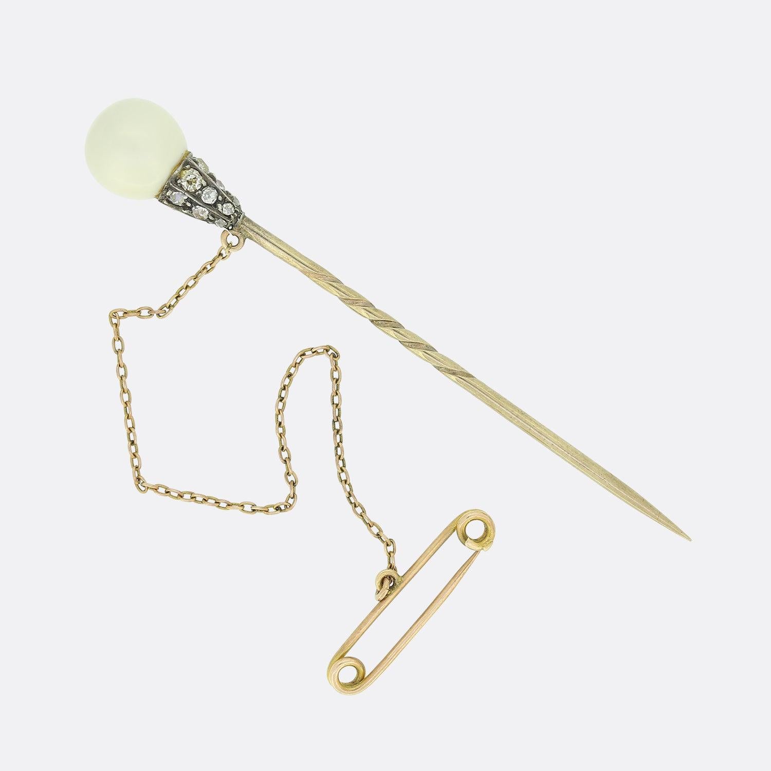 This is an antique pearl and diamond stick pin. The natural pearl features an impressive balance of tone and is a nice even shape. It sits above an old cut diamond set mount on a 9ct gold pin. The pin would have been crafted in 9ct as it is more