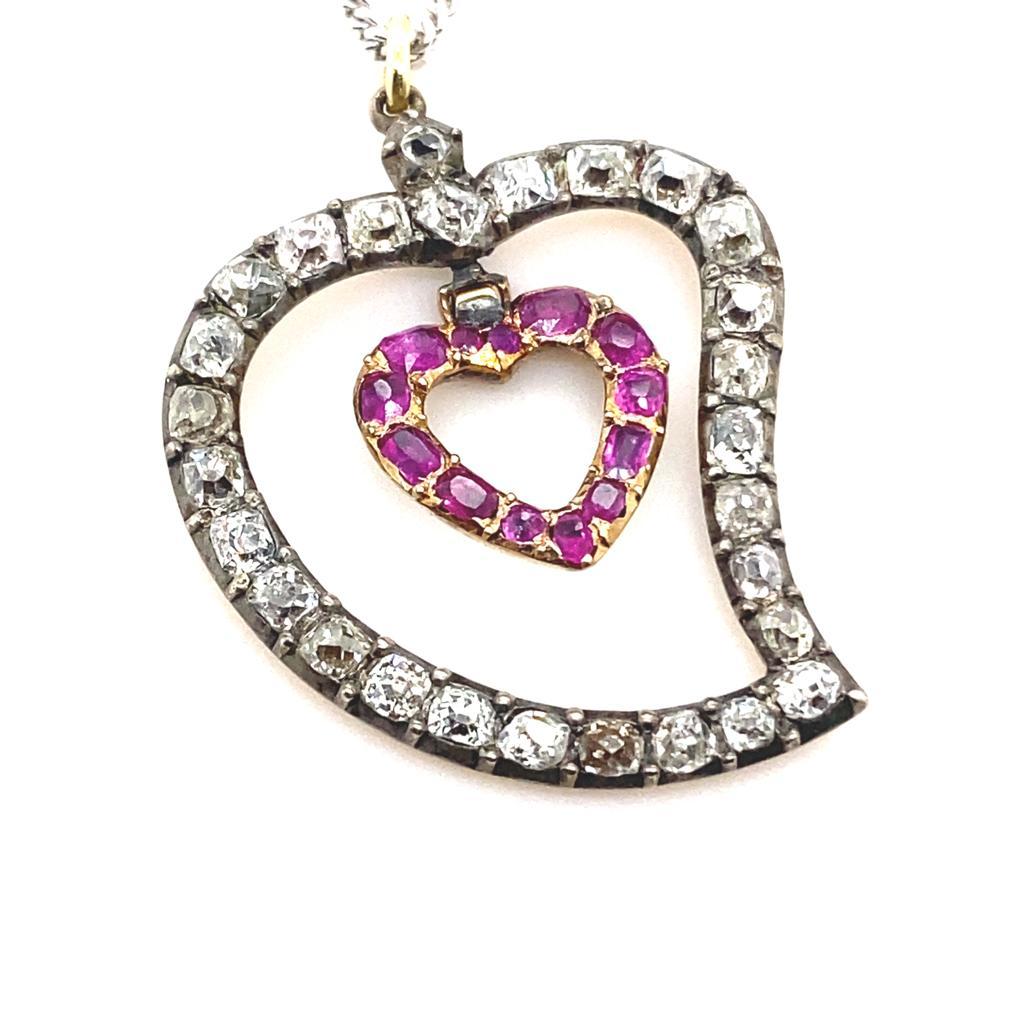 A Victorian diamond and ruby 'Beggars Heart' silver and yellow gold pendant.

This charming heart shaped pendant is composed of two hearts, one set within the other and both freely articulated. 

The outer heart is set with old mine cut diamonds in