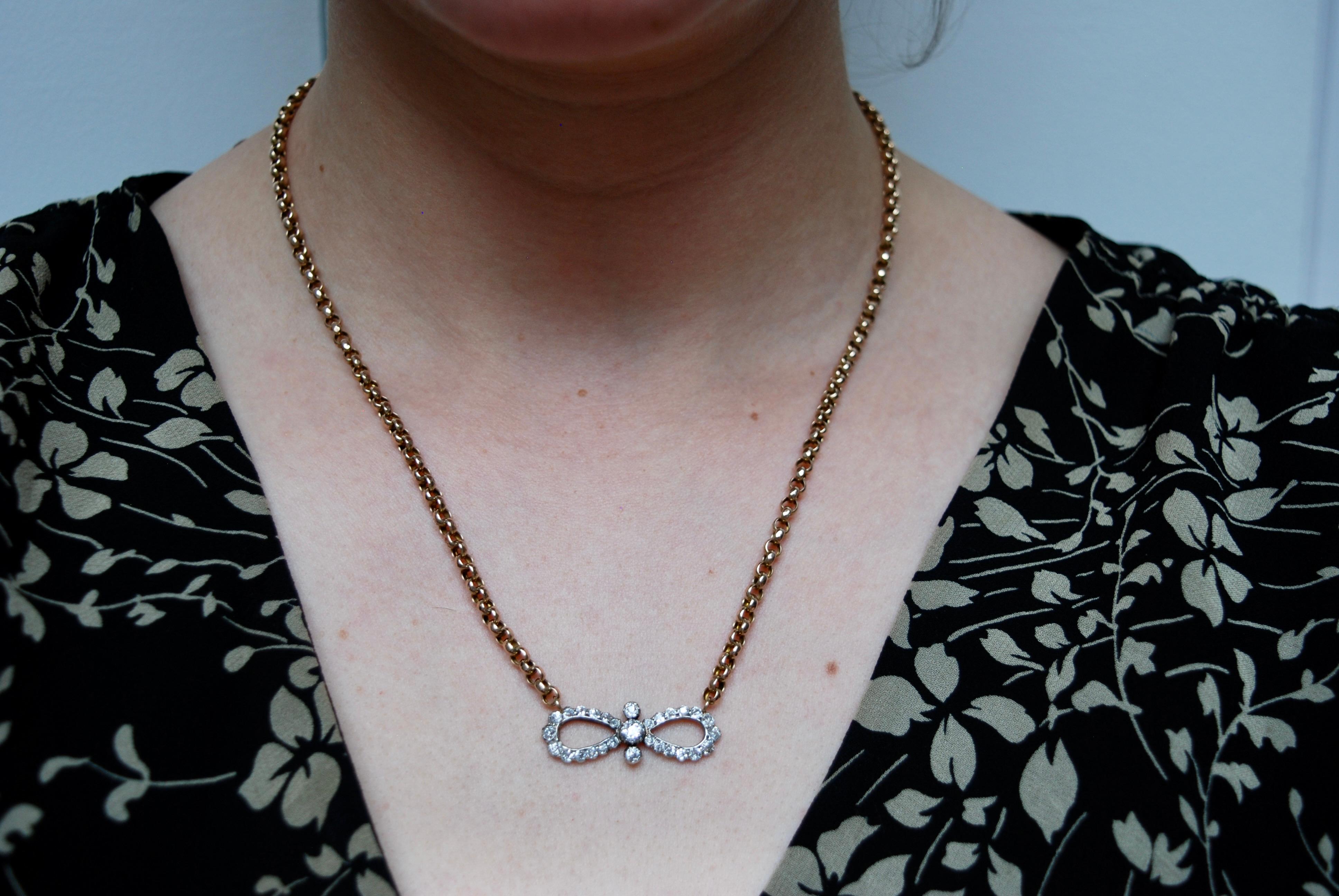 A mid 19th century diamond-set bow, the openwork bow design centred with three graduated diamonds flanked either side by a pendoloque hoop, set in silver and yellow gold with old brilliant-cut diamonds. Mounted on a yellow gold chain of a later