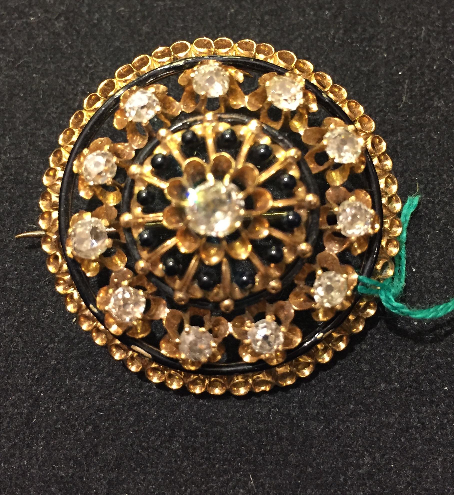 This stunning, fine and impressive Victorian diamond brooch has been crafted in 14 kt yellow gold and black enamel.
The pierced decorated setting displays a central feature 0.30 ct collet set Dutch cut diamond, encircled by eleven individually