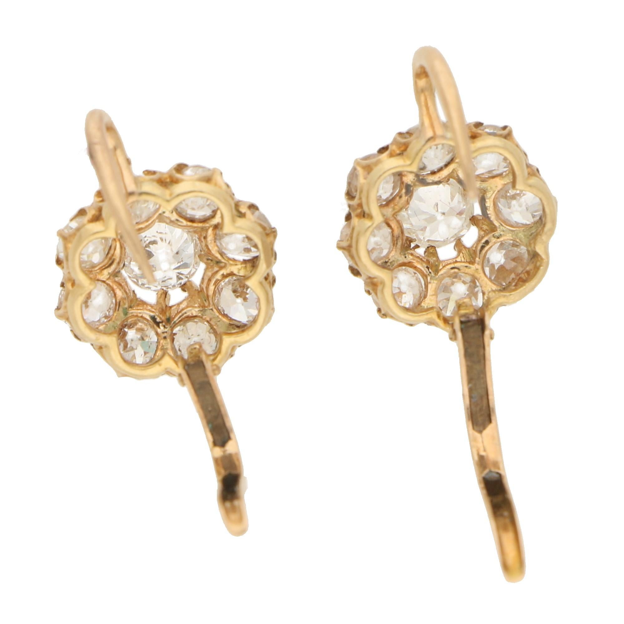 A sweet pair of Victorian diamond cluster earrings set in yellow gold. Each earring is set centrally with an old cut diamond which is clustered by a further single row of 8 eight-cut diamonds. The earrings are set on a hook with hinged back