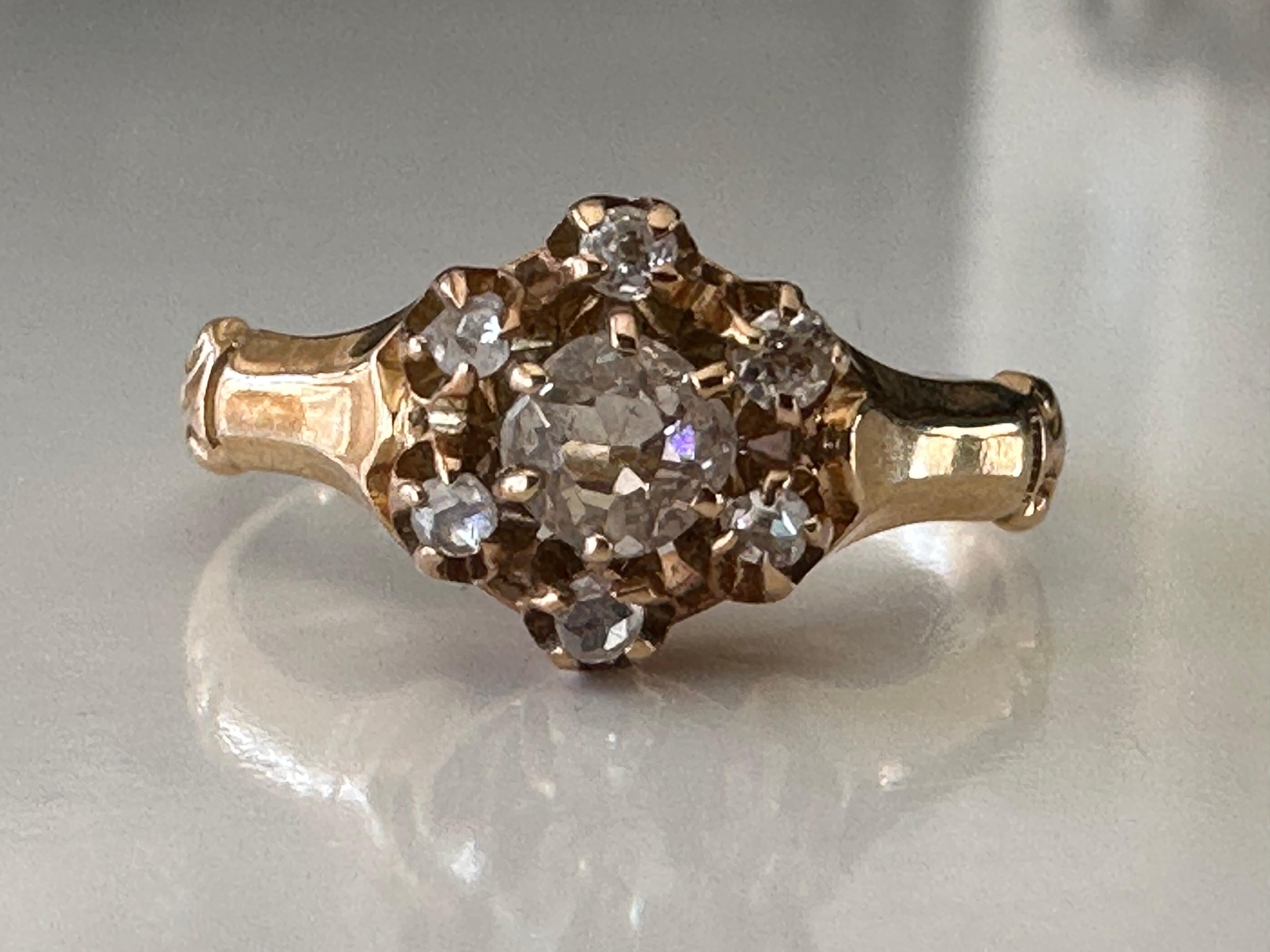 Crafted in the late nineteenth century in 10K yellow gold, this classic antique Victorian ring features a rose cut diamond center stone surrounded by a halo of Old Mine cut diamonds fashioned in a buttercup setting, a setting that dates back to the