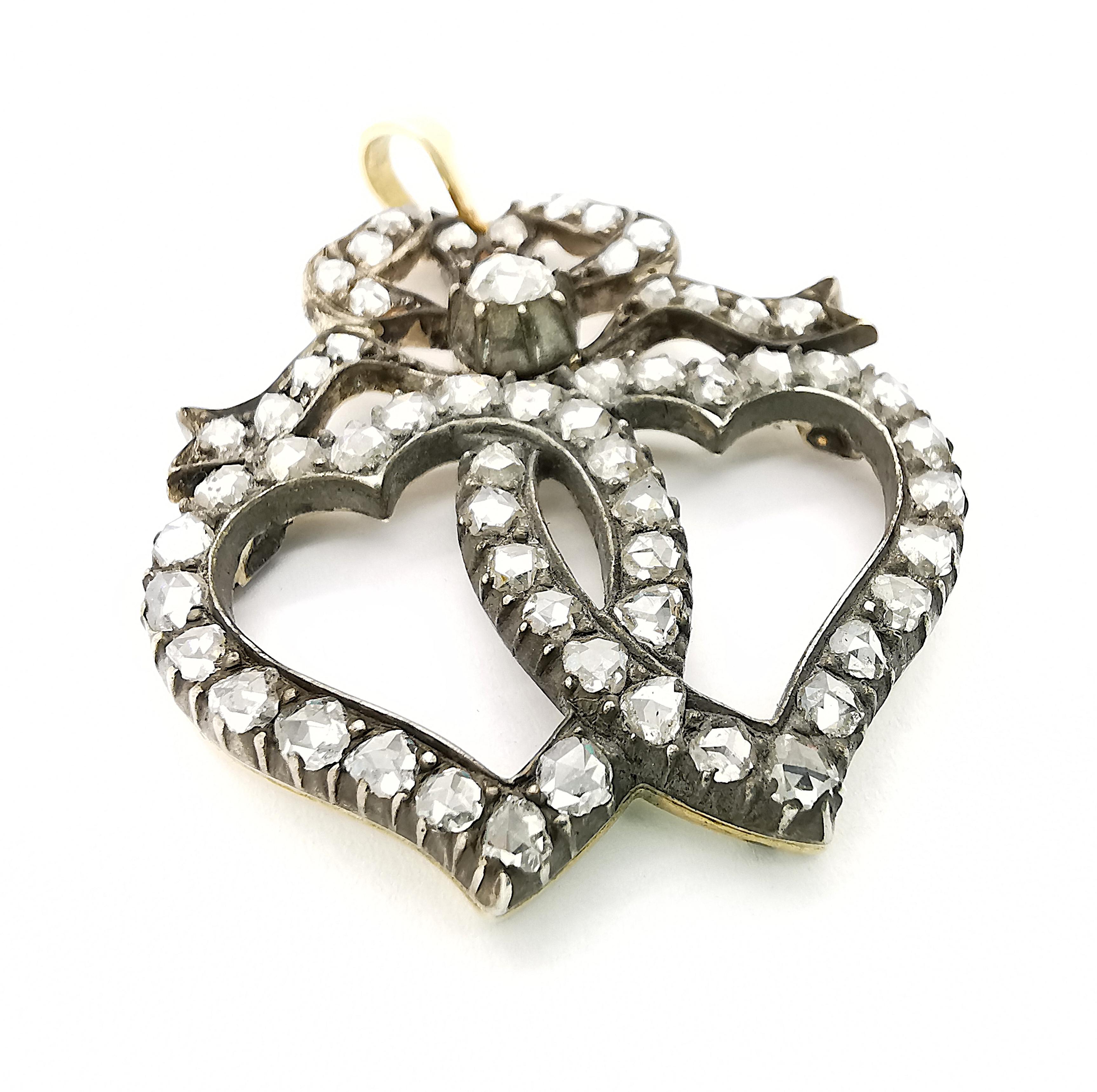 A Victorian diamond set, Luckenbooth double witches' heart pendant, with rose cut diamonds set in the two hearts and bow, weighing an estimated total of 1.50ct, in grain and cut down settings, mounted in silver-upon-gold. Circa 1880.

Luckenbooth