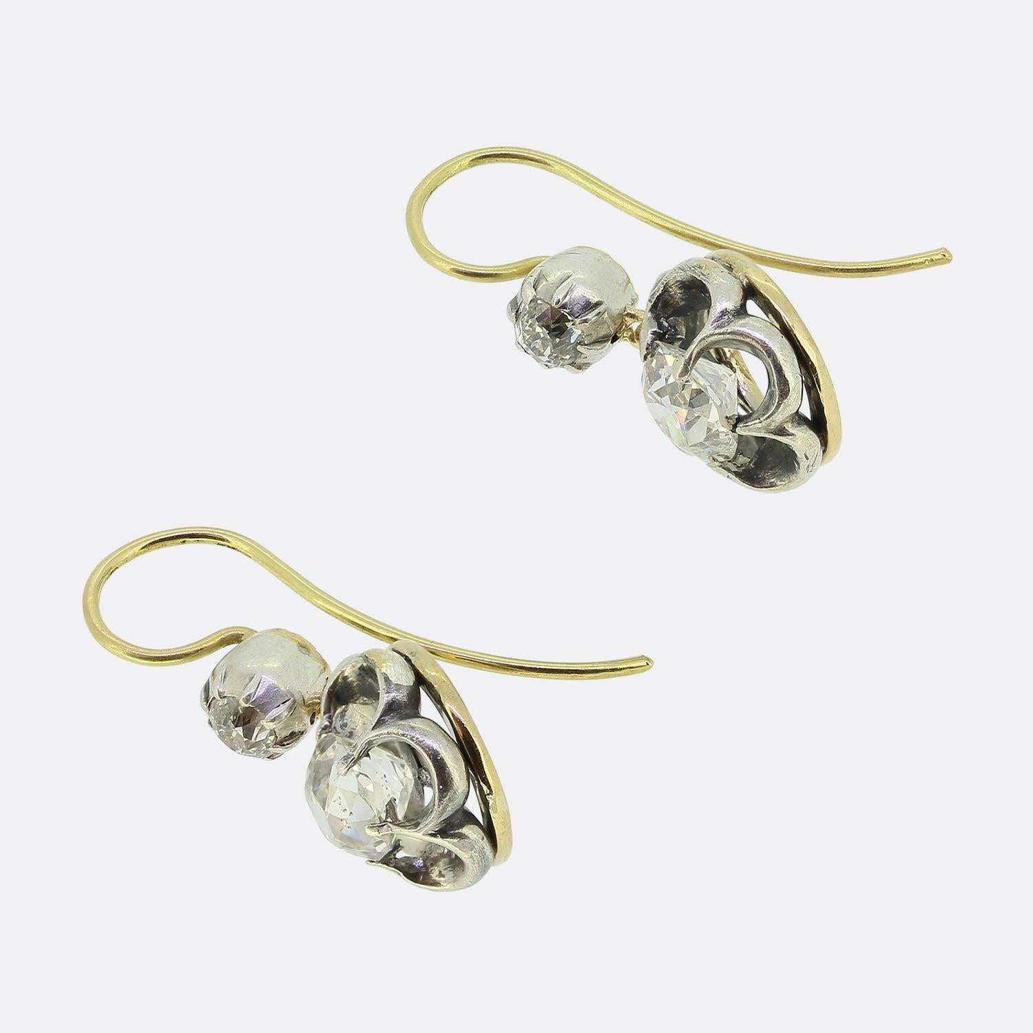 This is an exquisite pair of Victorian drop earrings. Each earring is set with a large, antique cushion cut diamond and a small old cut diamond accent set above. The earrings have French wire fittings which sit very comfortably on the ear and allow