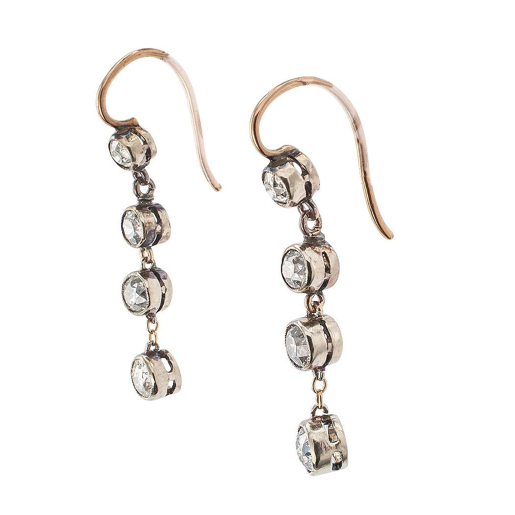 Victorian diamond silver and gold drop earrings circa 1890. The matching designs feature old cut diamonds set in silver bezels with link connectors to the matching surmounts, the eight diamonds totaling approximately 1.20 carats, approximately I – K