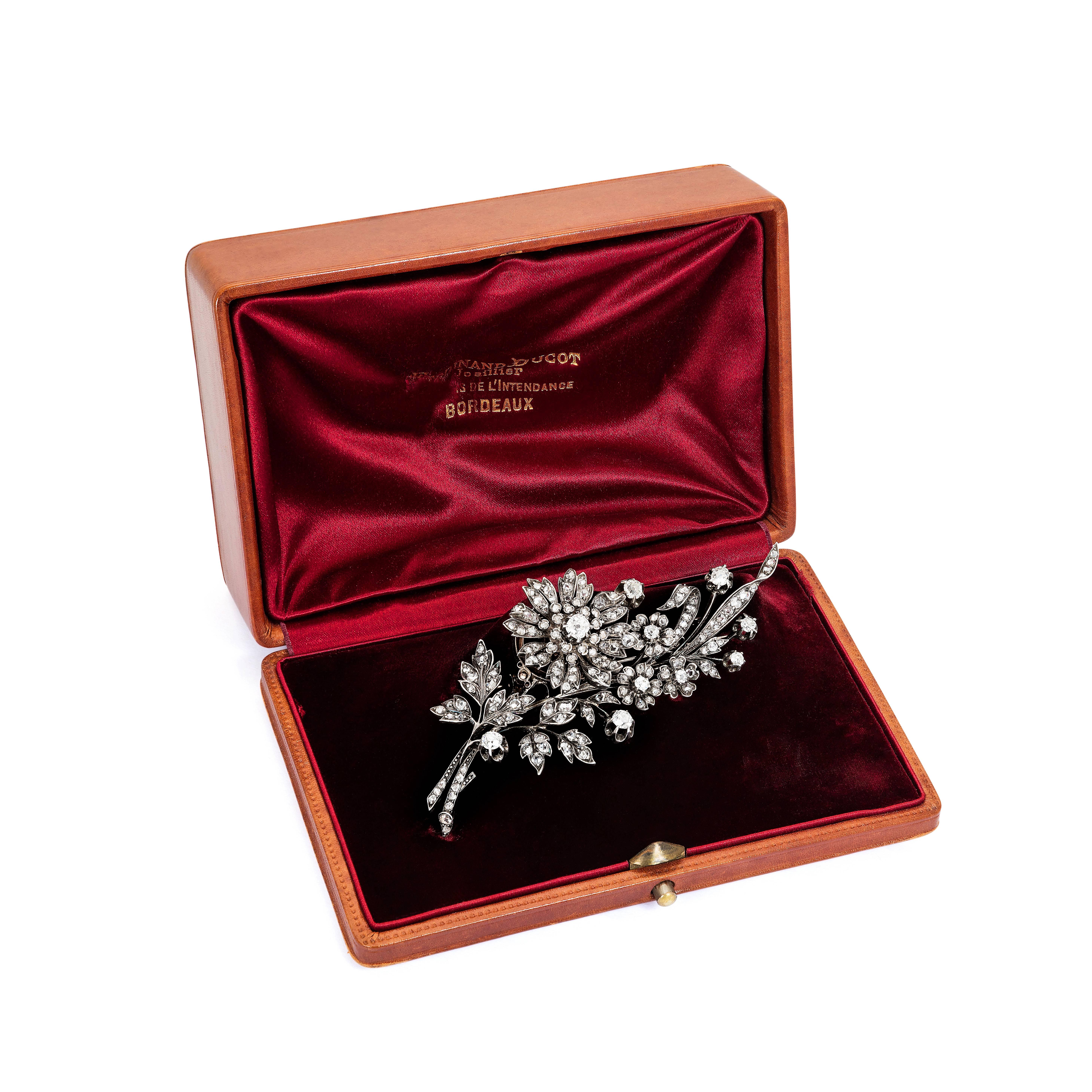A Victorian diamond floral brooch. The elegant floral spray is animated by a ‘en tremblant’ setting for the largest flower in the centre. Small rose-cut diamonds surround larger round-cut cushion diamonds. The stones are set in silver on a gold