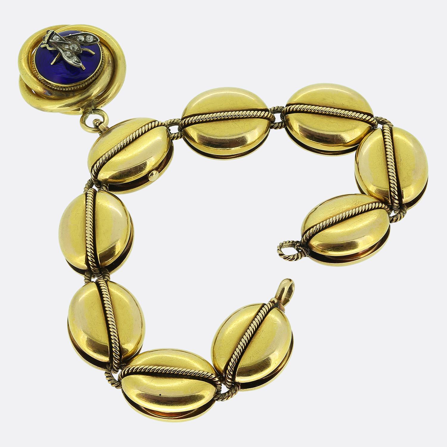 Ecco un braccialetto vittoriano unico, realizzato in oro giallo 18 carati. Il design è caratterizzato da una serie di maglie ovali e lisce in oro, ognuna con un dettaglio di corda attorcigliata che attraversa il centro. Un medaglione di grande