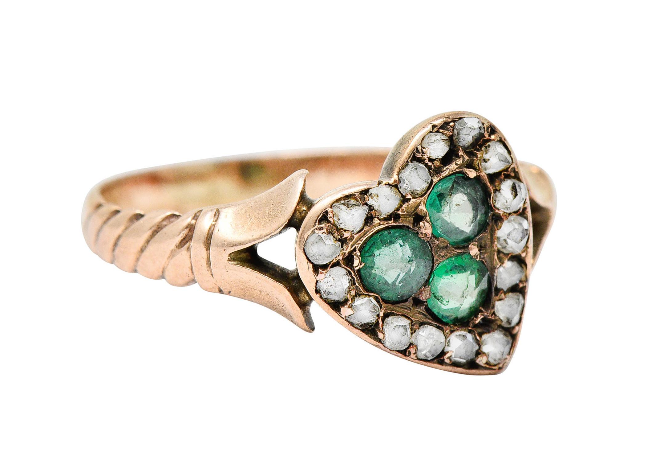 Band ring features a heart motif that centers three round cut green paste gemstones - well matched

With a rose cut diamond halo - color and quality consistent with age

Completed by stylized tulip shoulders and ribbed texture

Tested as 14 karat