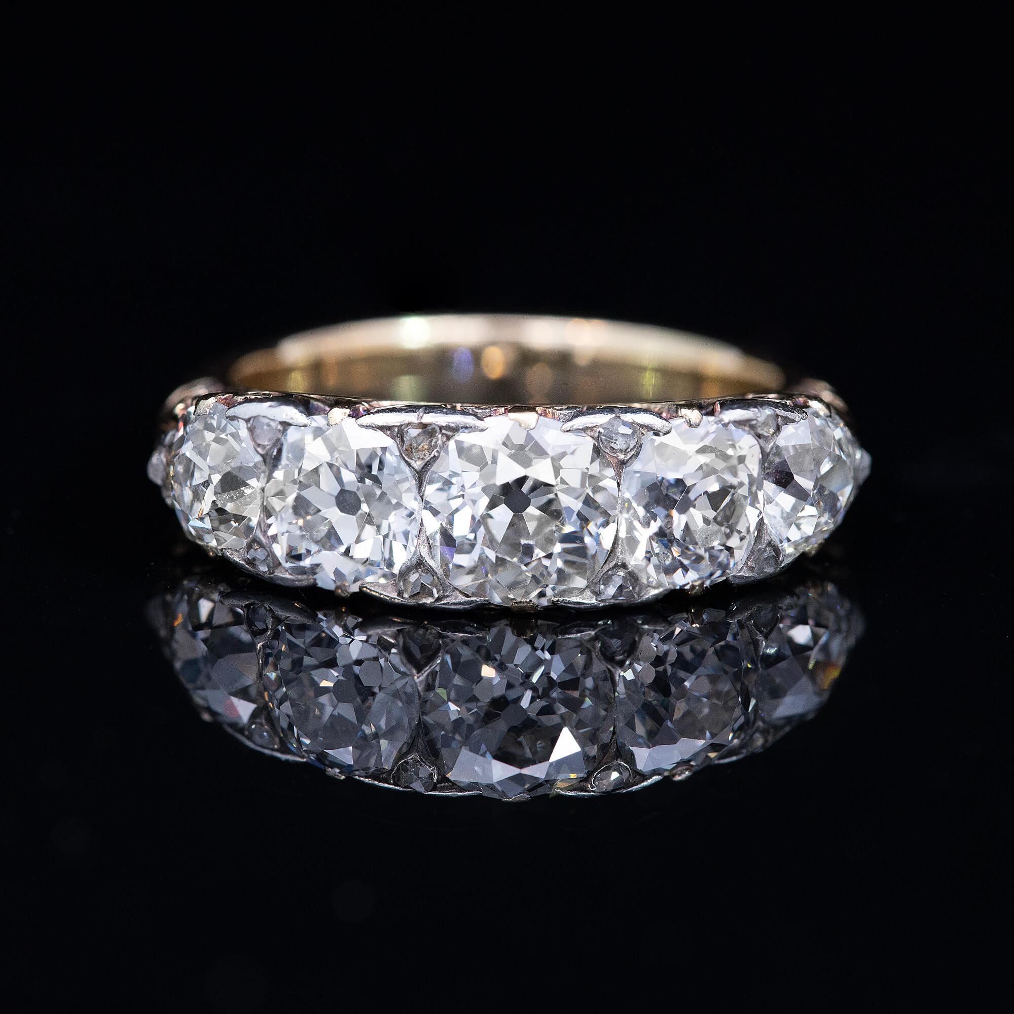 A Victorian half hoop ring featuring early European cut and mixed cut diamonds. A beautifully carved scrolled shoulders and a fancy two tone filigree carved undercarriage sets the stage for the bead set diamonds. Engraved with old script “944”.