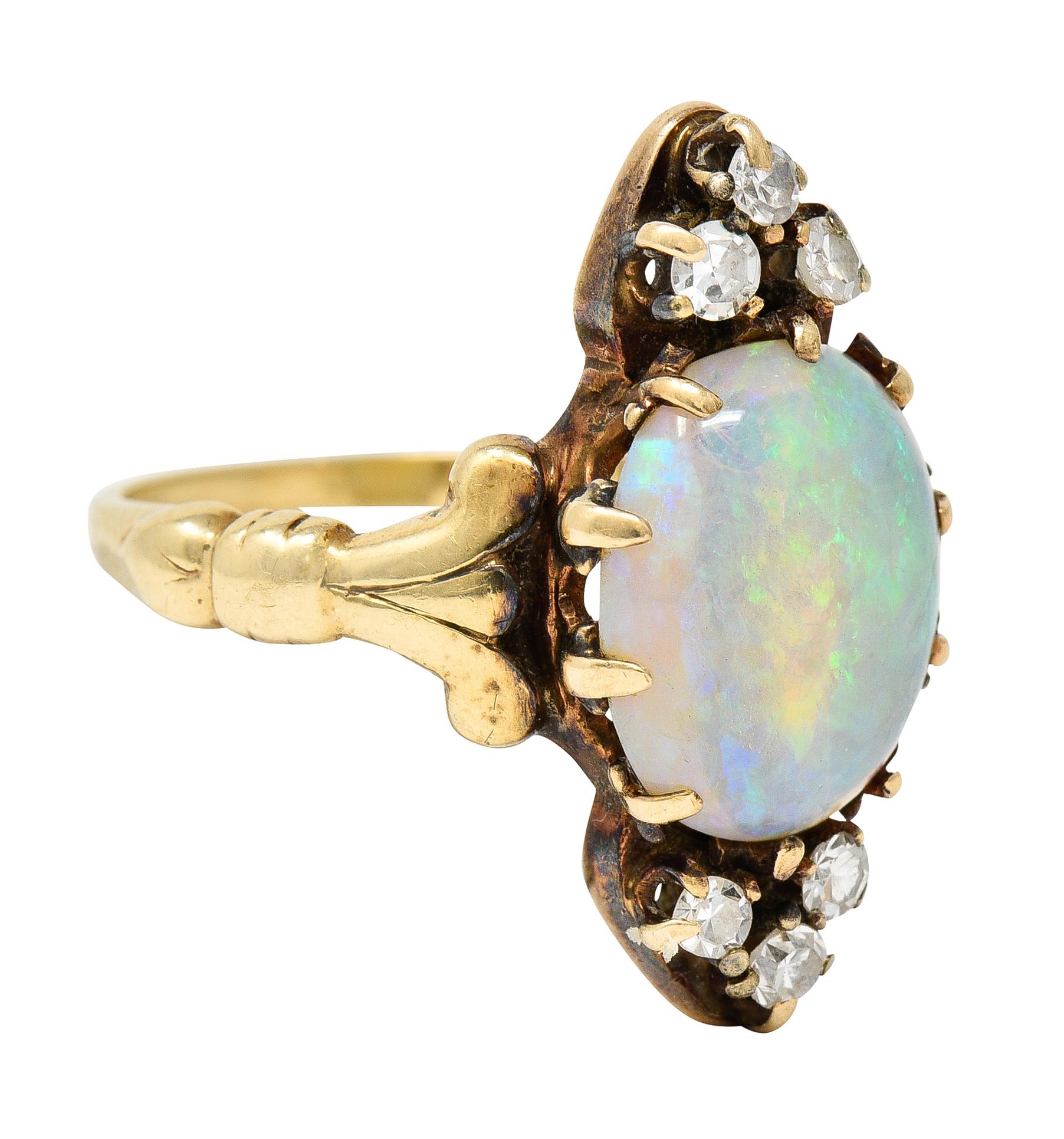 Ring centers a 10.0 x 11.5 mm oval cabochon opal - white in body color with spectral play-of-color

Set with stylized trefoil prongs and flanked North to South by six single cut diamonds

Prong set and weighing approximately 0.18 carat total - eye