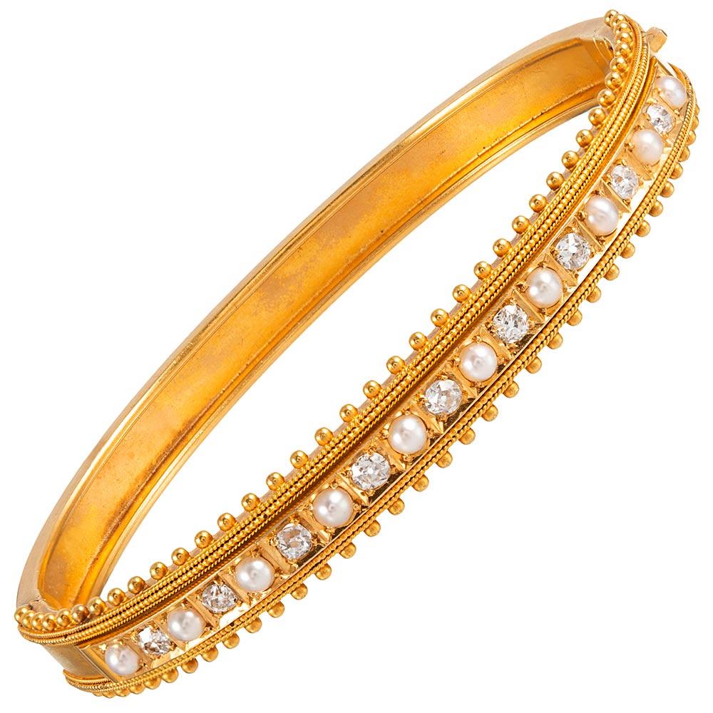 Made of 15 karat yellow gold, the bangle is set with alternating brilliant white diamonds and lustrous pearls- an classic combination that will mis well with all of your other Victorian treasures. 2 1/4 by 1 7/8 inches in interior diameter and