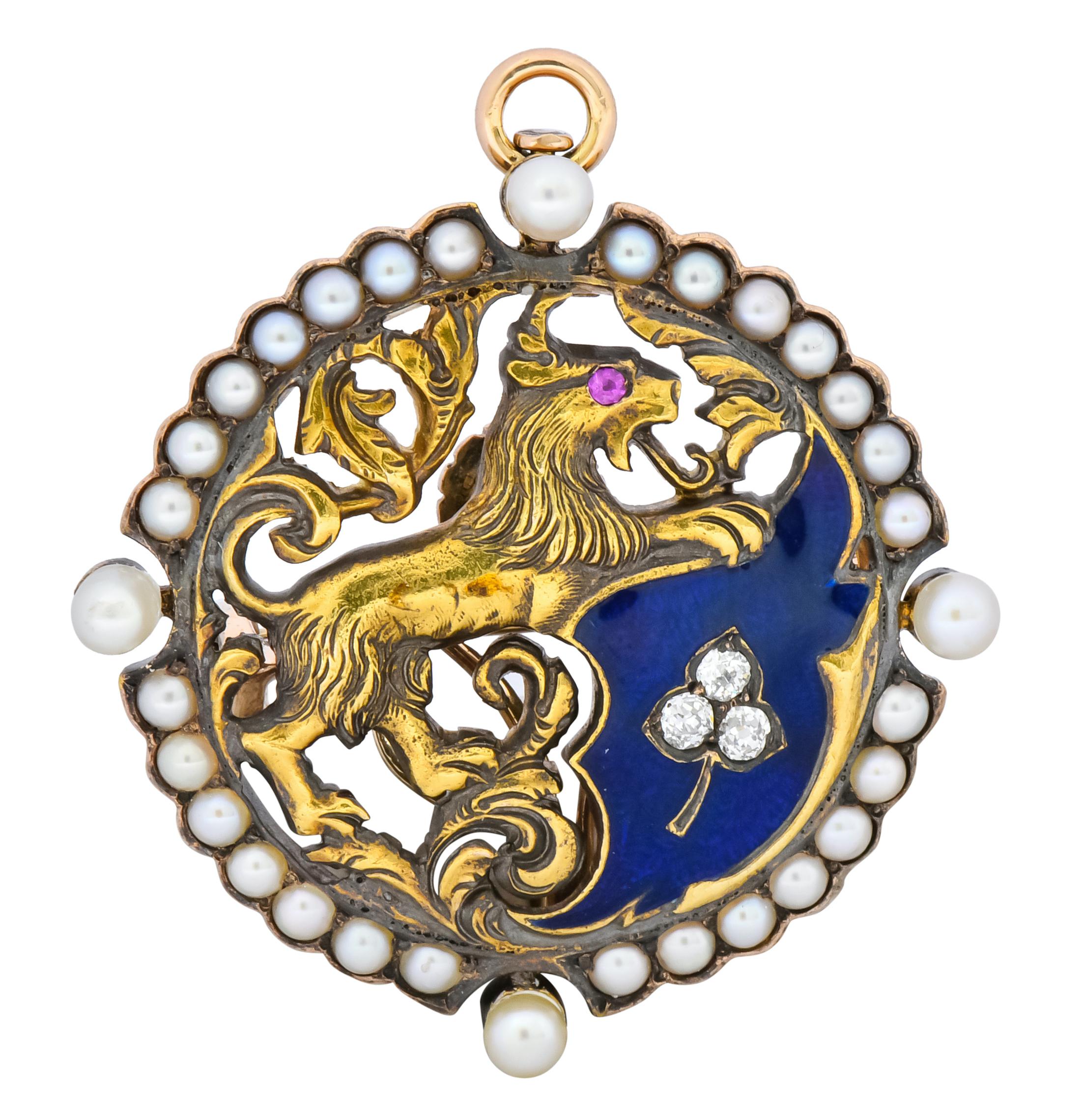 Featuring a 14 karat gold setting containing a stylized lion in reared stance with whiplash and foliate detail

Blue enamel field with three bead set old mine cut diamonds within a leaf motif

With a ruby accent for the lion’s eye and four round