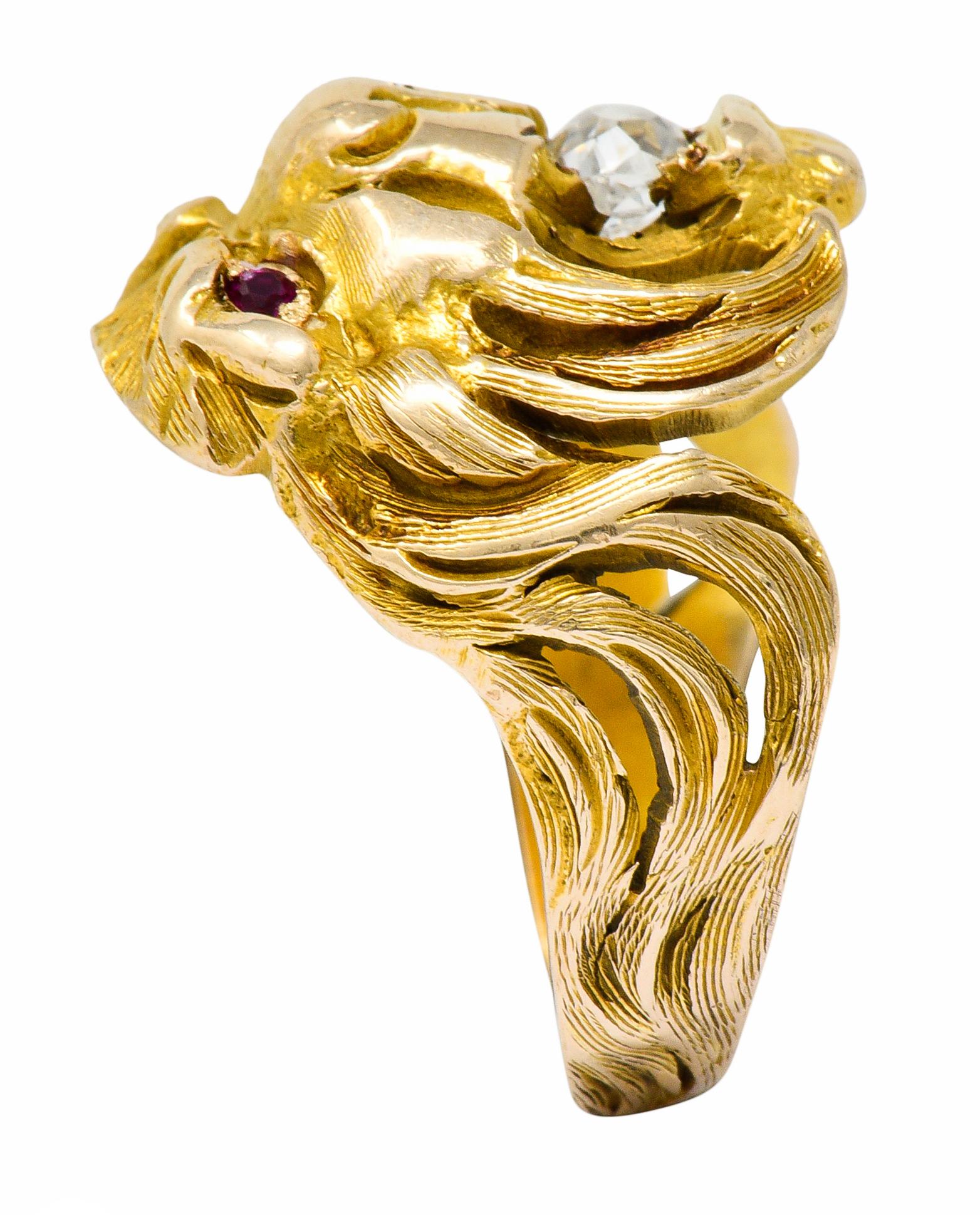 Band ring is highly rendered to depict a roaring lion with a flowing mane

With an old mine cut diamond clutched in its jaws weighing approximately 0.33 carat; I color with SI clarity

Accented by round cut ruby eyes; well-matched and bright