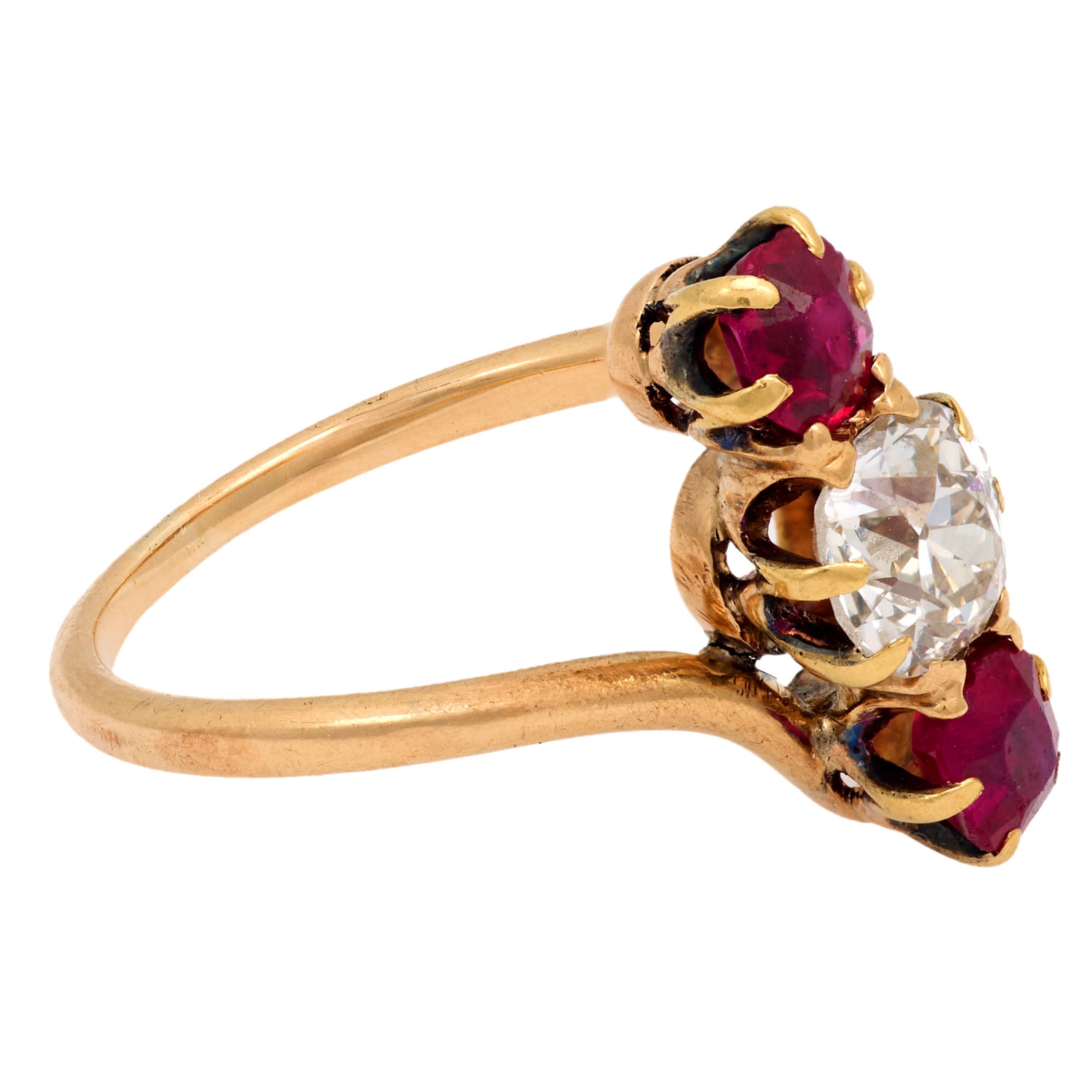 This Victorian 14k yellow gold ring features a glowing .60 carat old mine cut diamond flanked by two vibrant cushion cut rubies. Crafted around 1900, its refined silhouette and rich contrast embody timeless antique elegance in a delicate, romantic