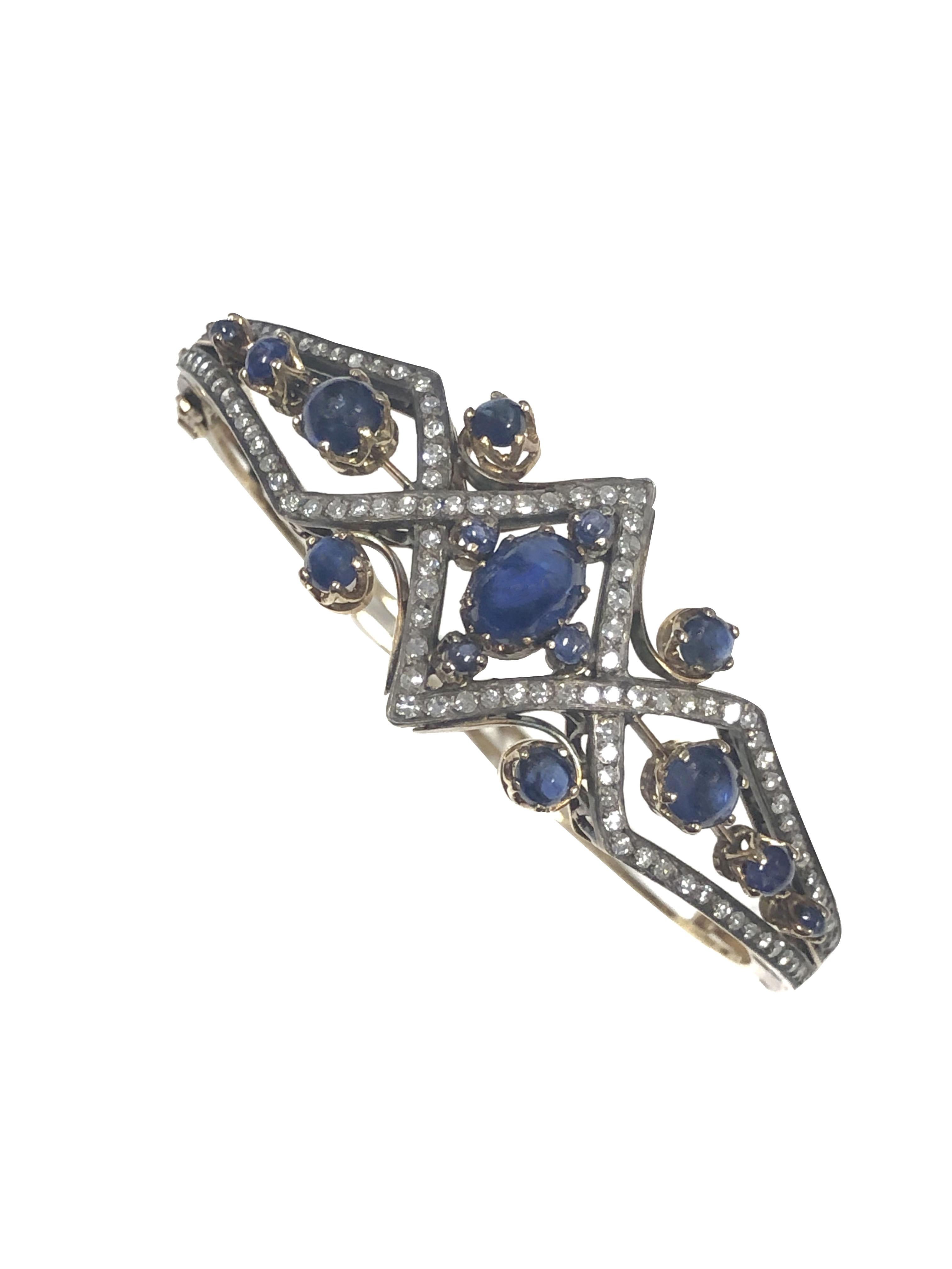 Circa 1910 Bangle Bracelet, 15K Yellow Gold with a Silver top, set with Old cut Diamonds totaling approximately 1.25 Carats and further set with very Fine color Cabochon Sapphires. Measuring just under 1 inch wide at the very center of the top and