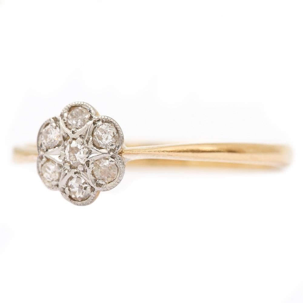 A pretty Victorian diamond seven stone petal or daisy cluster ring set in 18 karat yellow gold that is a large UK U, US10 ¼, EU 62¾. The style is ideal as as a dainty stackable ring. 

The head of the ring has seven Old Mine cut diamonds that are