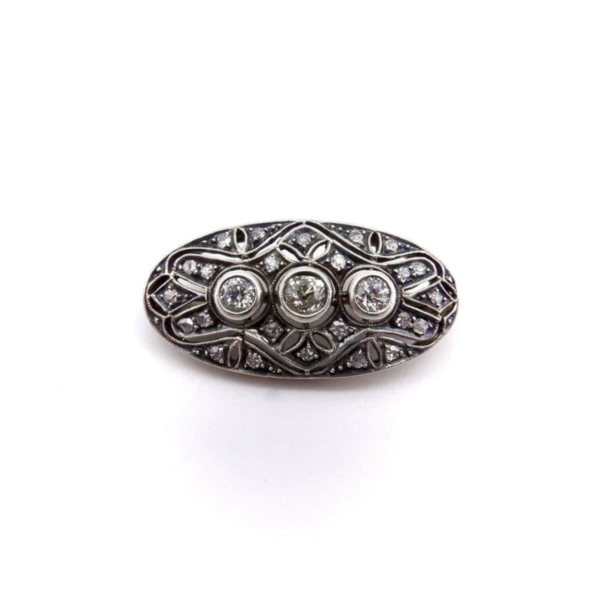 This Victorian-era brooch contains three Old Mine cut diamonds, surrounded by 24 smaller rose and single cut diamonds. The front of the brooch is made of silver; its tarnished patina creates a gorgeous chiaroscuro effect, highlighting the sparkling
