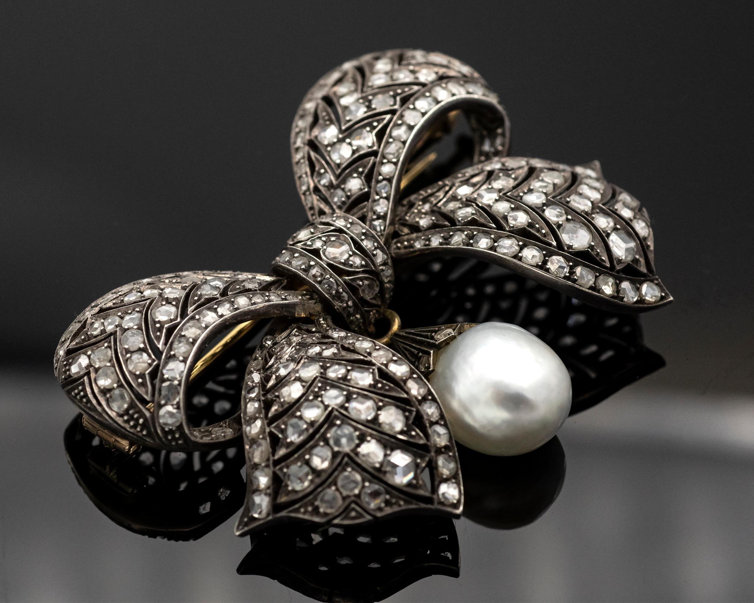 Exquisite Victorian silver topped 18K gold bow brooch set with rose cut diamonds, from which a removable  mm pearl hangs .

It can also be worn as a necklace thanks to two hoops.