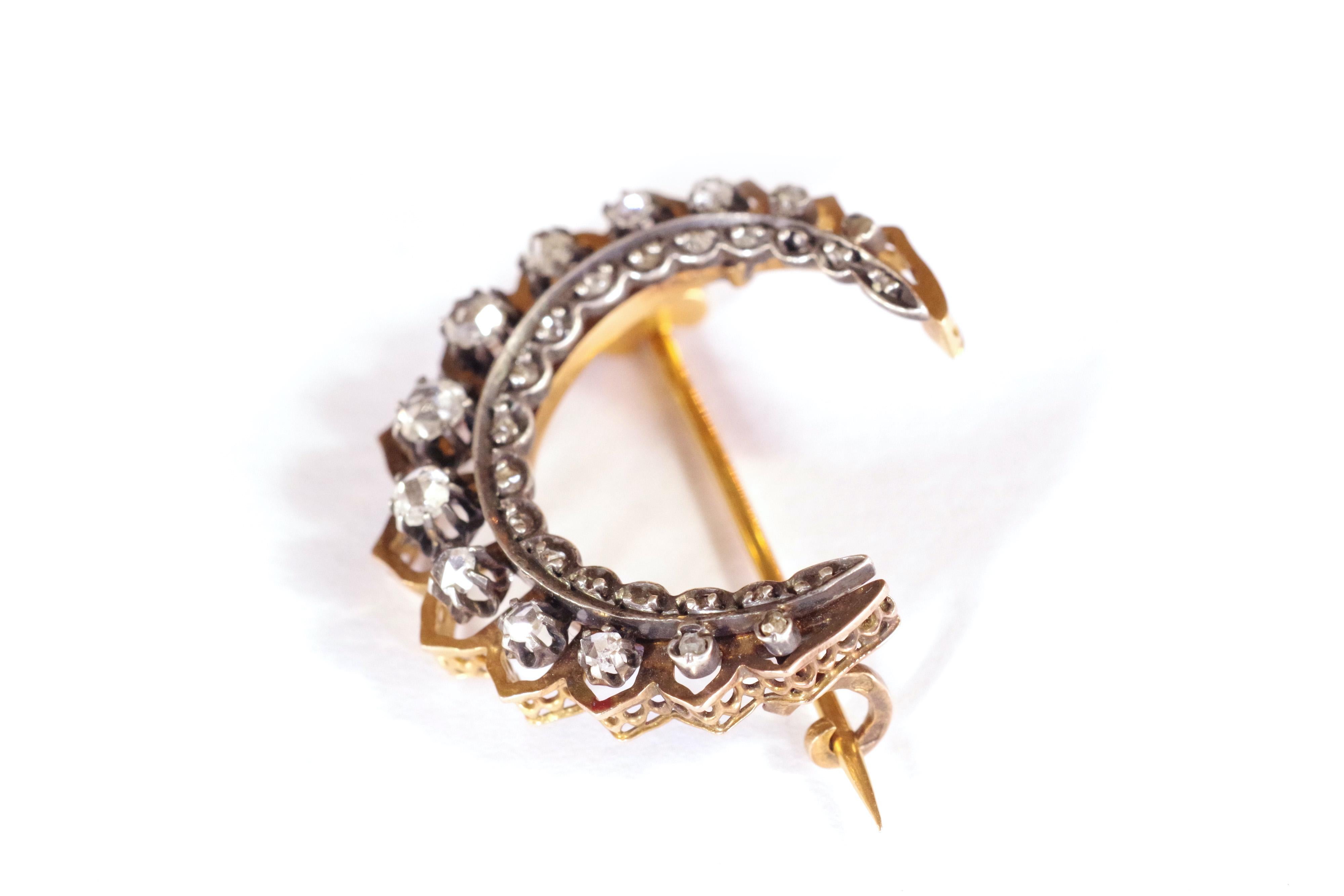 Victorian diamonds crescent moon brooch in 18 karat rose gold and silver. The brooch takes the shape of a crescent moon. The crescent is decorated with thirteen diamonds cut in Dutch rose, and set by claws. These diamonds are highlighted by an