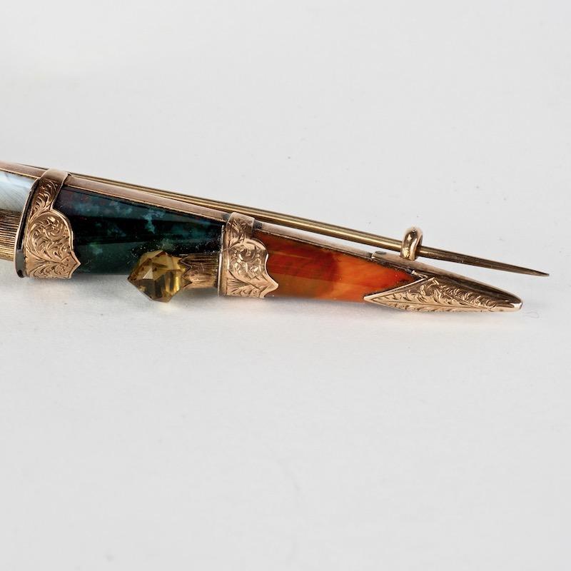 Victorian Dirk Brooch set with gemstones of Montrose agate, bloodstone, citrine, Cairngorm quartz and jasper mounted in an antique gold filigree and scrollwork brooch in the form of a Scottish dirk or dagger traditionally worn in highland dress.