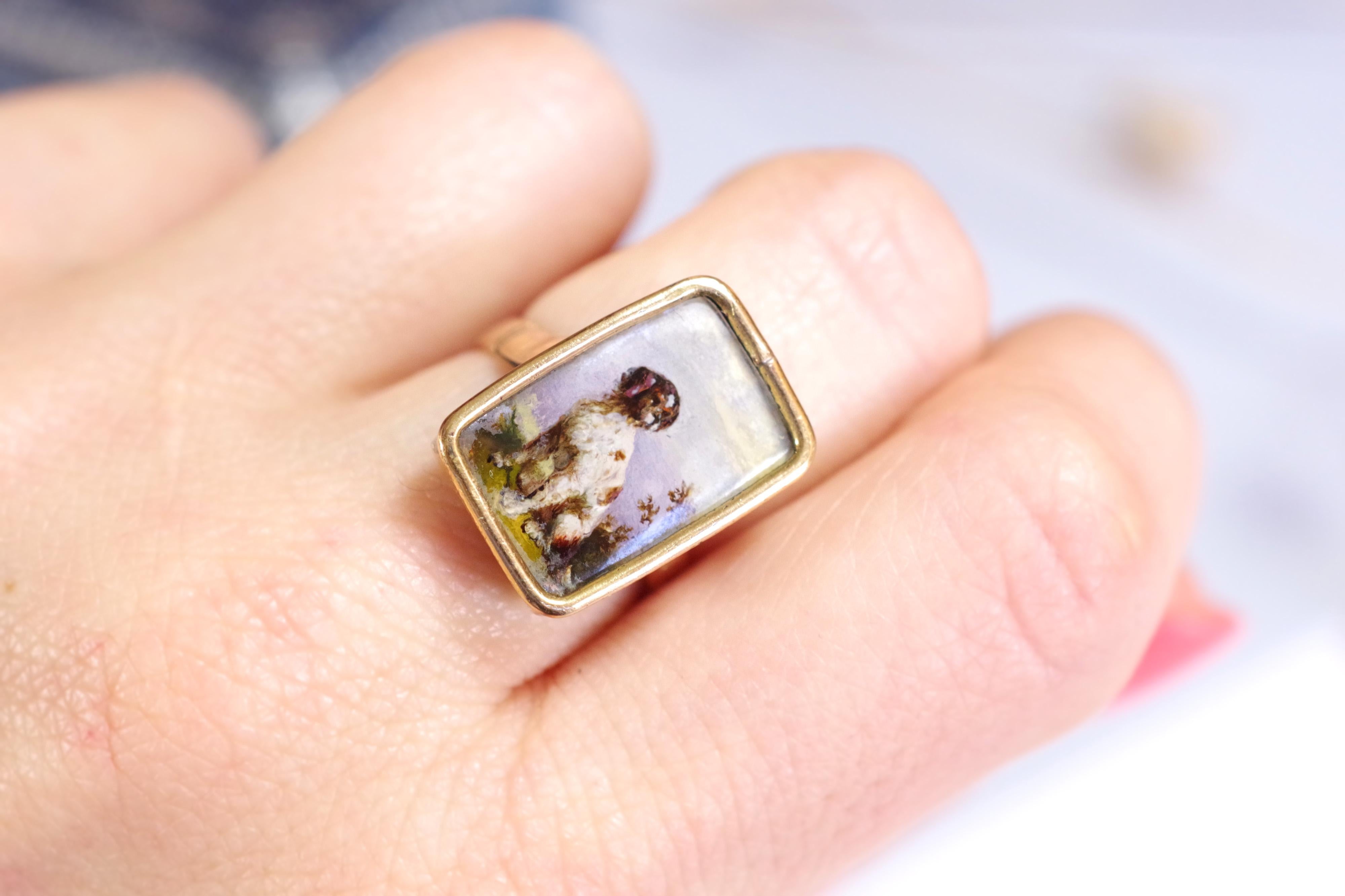 Victorian Spaniel brittany dog ring in rose gold 9 karats. Antique ring with a painted miniature, showing a sitted dog, looking to the right. It is most probably a hunting dog, Spaniel Brittany type. The miniature is painted on a white background.