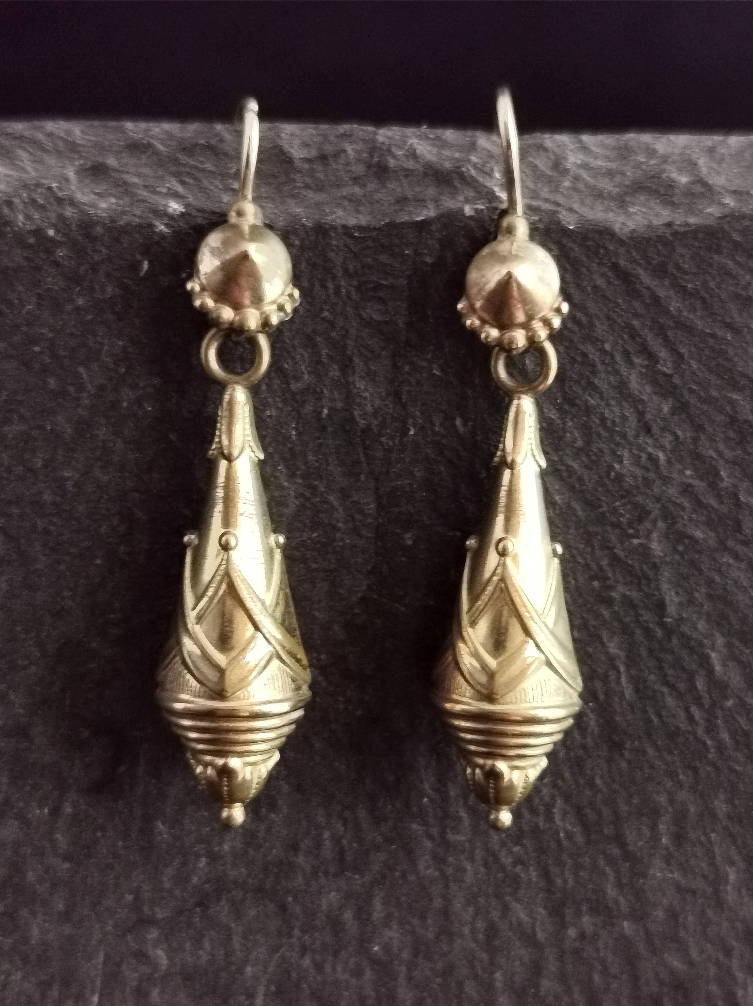 A beautiful pair of Victorian torpedo style drop earrings.

Elongated drops with a light repousse design in an Etruscan revival style.

The earrings have an ear wire or hook fitting for pierced ears.

They are hollow so are lightweight and easy to