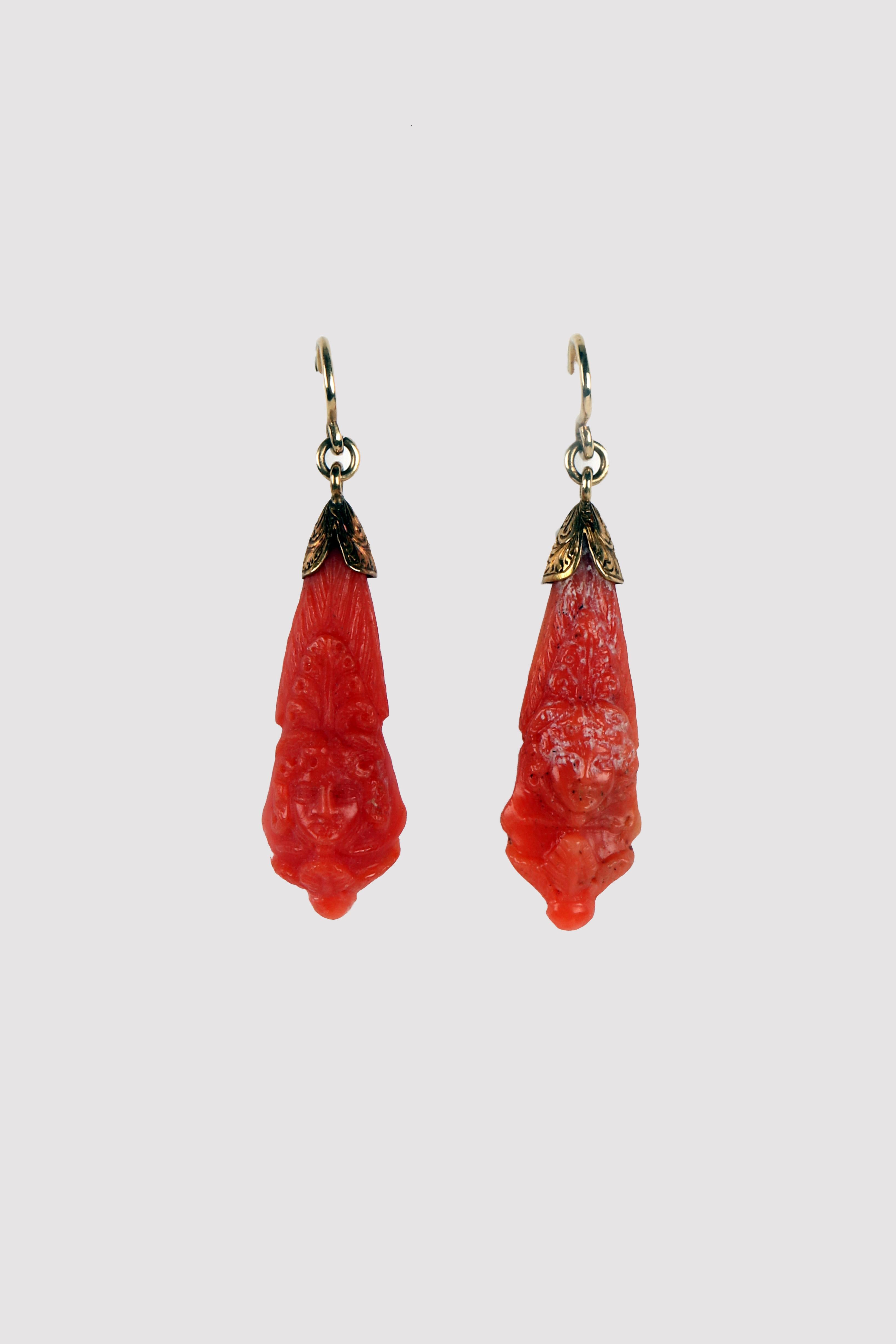 Victorian earrings in gold and coral. A smooth shank gold hook supports a connecting ring, to which the pendant is connected. Supported by a double chiselled gold leaf motif, the pendant is cut and engraved in Sciacca (Sicily) coral , forming an