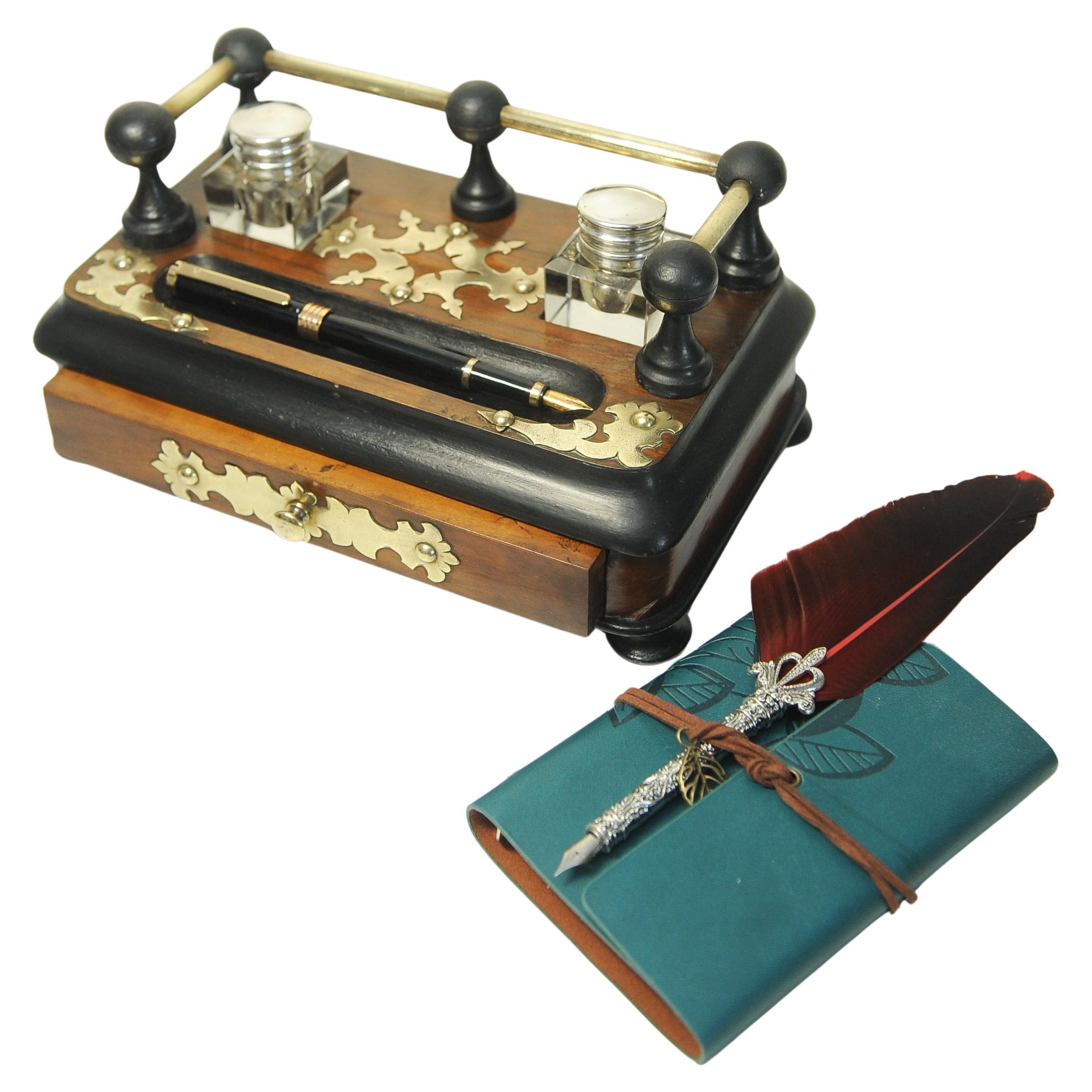 Charmant rangement de bureau victorien en ébonite avec deux encriers en verre taillé, avec d'attrayants rails en laiton, des motifs décoratifs et un tiroir.

Livré avec une plume d'oie moderne, un bloc-notes et un stylo plume Ronson dans un coffret
