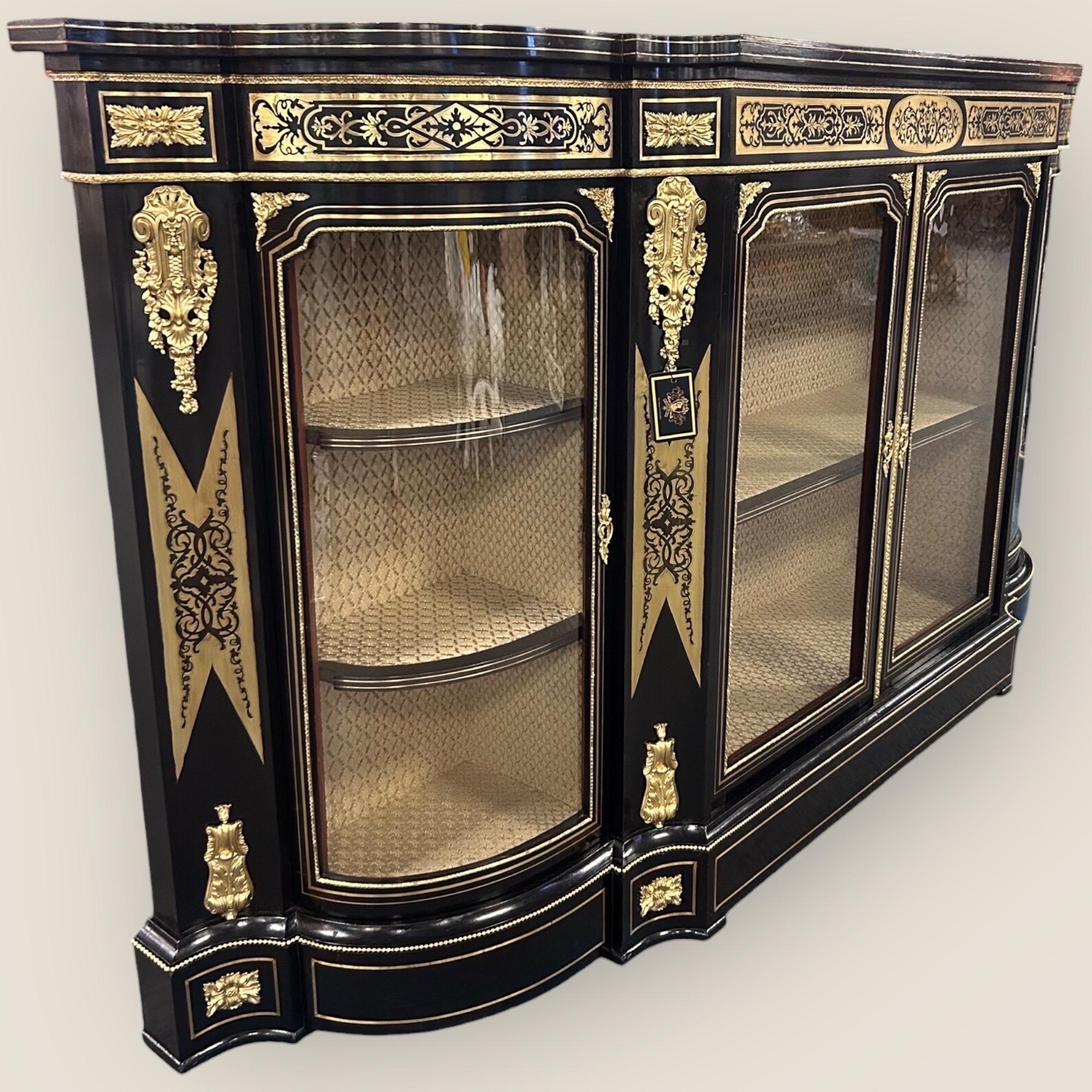 Large Victorian (1837-1901) Ebonised Serpentine shaped Boulle Credenza. With intricate boulle inlay and ormolu brass on the frieze and the four columns. With an ebonised top and brass detailing on the base. The credenza has 4 glazed panelled doors,