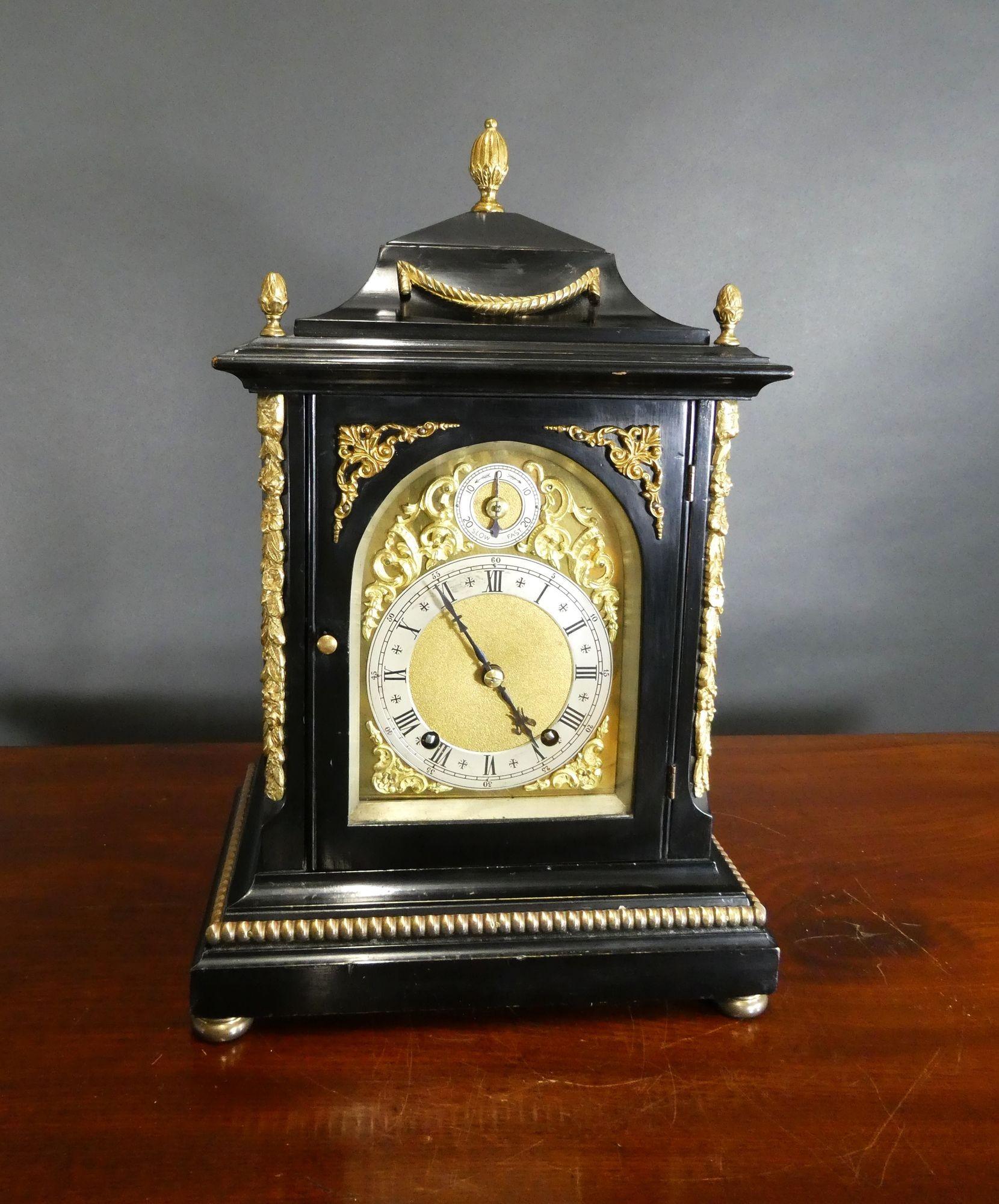 Victorian Ebonised Ting-Tang Mantel Clock
Victorian mantel clock housed in an ebonised case with applied ormolu mounts, raised stepped plinth with rope decoration and standing on four brass bun feet. Decorated gilded pillars to either side of the