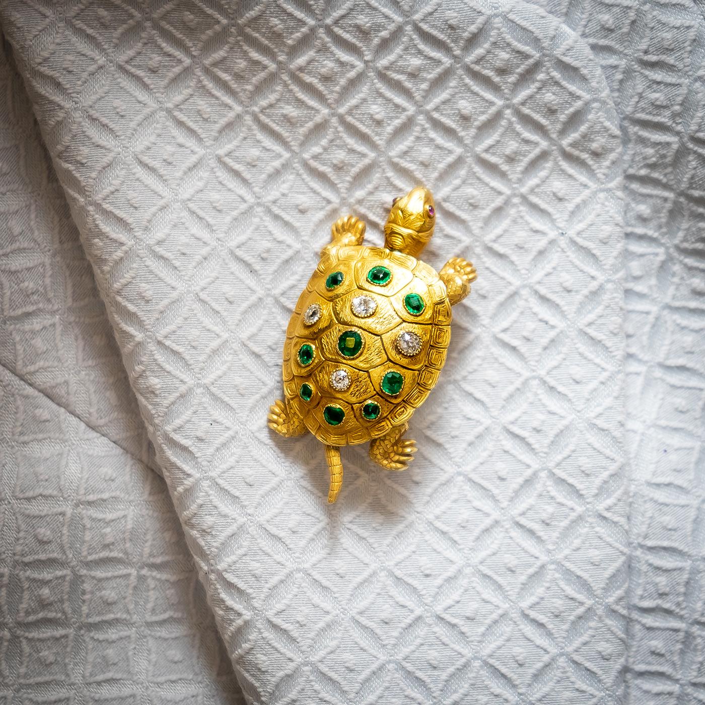 A French turtle brooch, by Edmond Plisson, with sprung moving head, legs and tail, the shell is set with cushion shaped emeralds and old-cut diamonds, in millegrain edged rub over settings, mounted in 18ct gold, engraved to represent the shell and