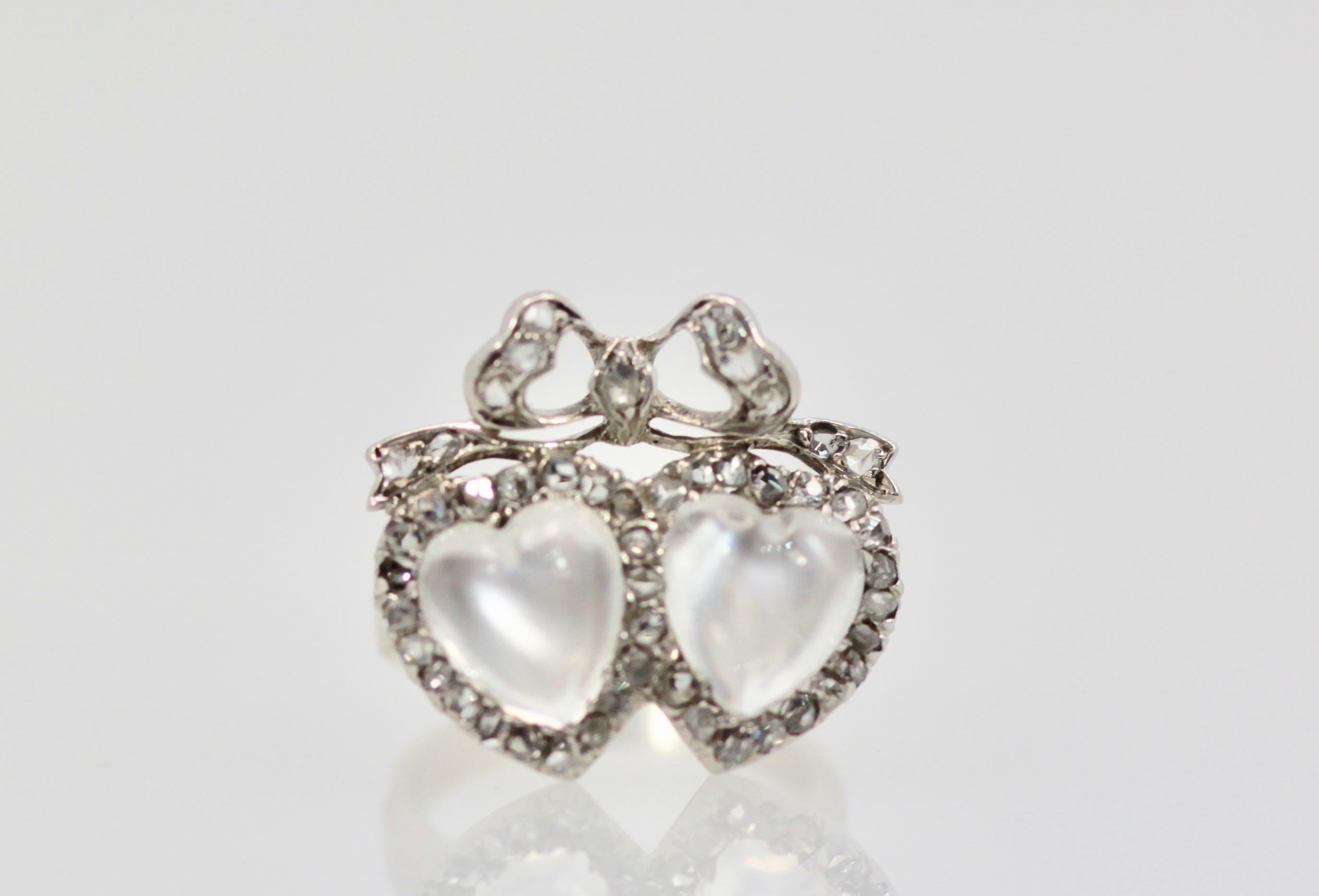 This lovely Victorian double heart moonstone ring is set in Platinum and 18K white gold.  To further enhance it there is a Diamond bow centered on top.  This motif is very Victorian and I purchased this out of England where Victorian/Edwardian