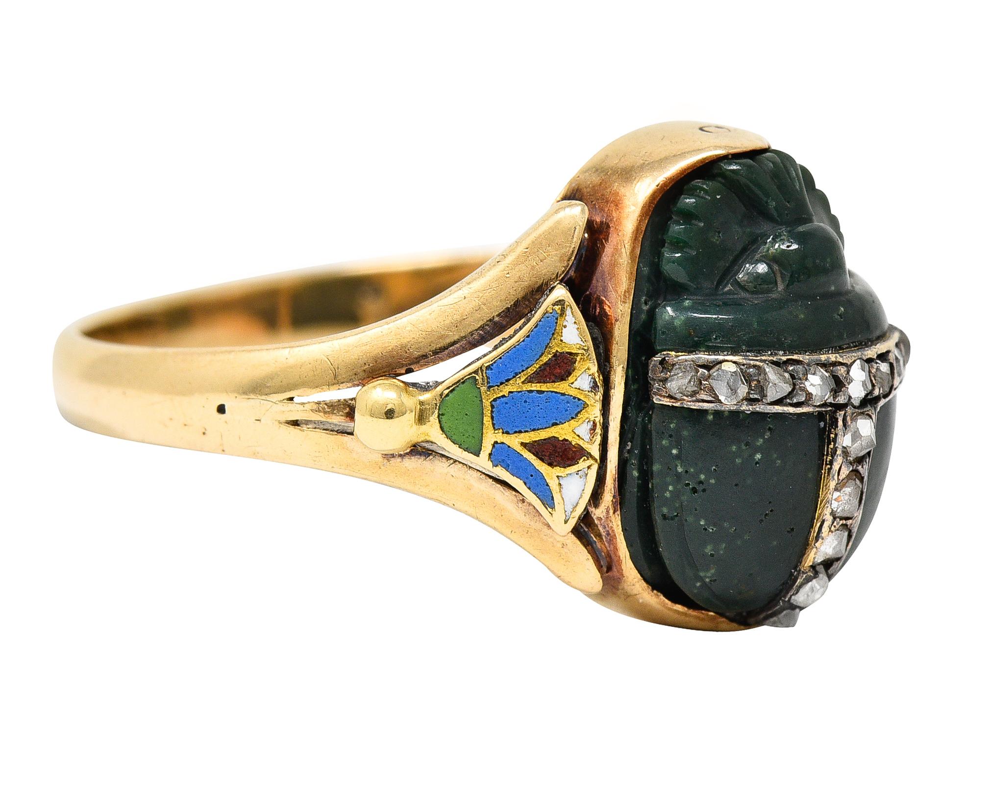 Centering a nephrite cabochon carved to depict a scarab beetle - measuring 9.0 x 12.0 mm. Opaque dark bluish green in color - accented by bands of rose cut diamonds across beetle. Bead set and weighing approximately 0.14 carat total - eye clean and