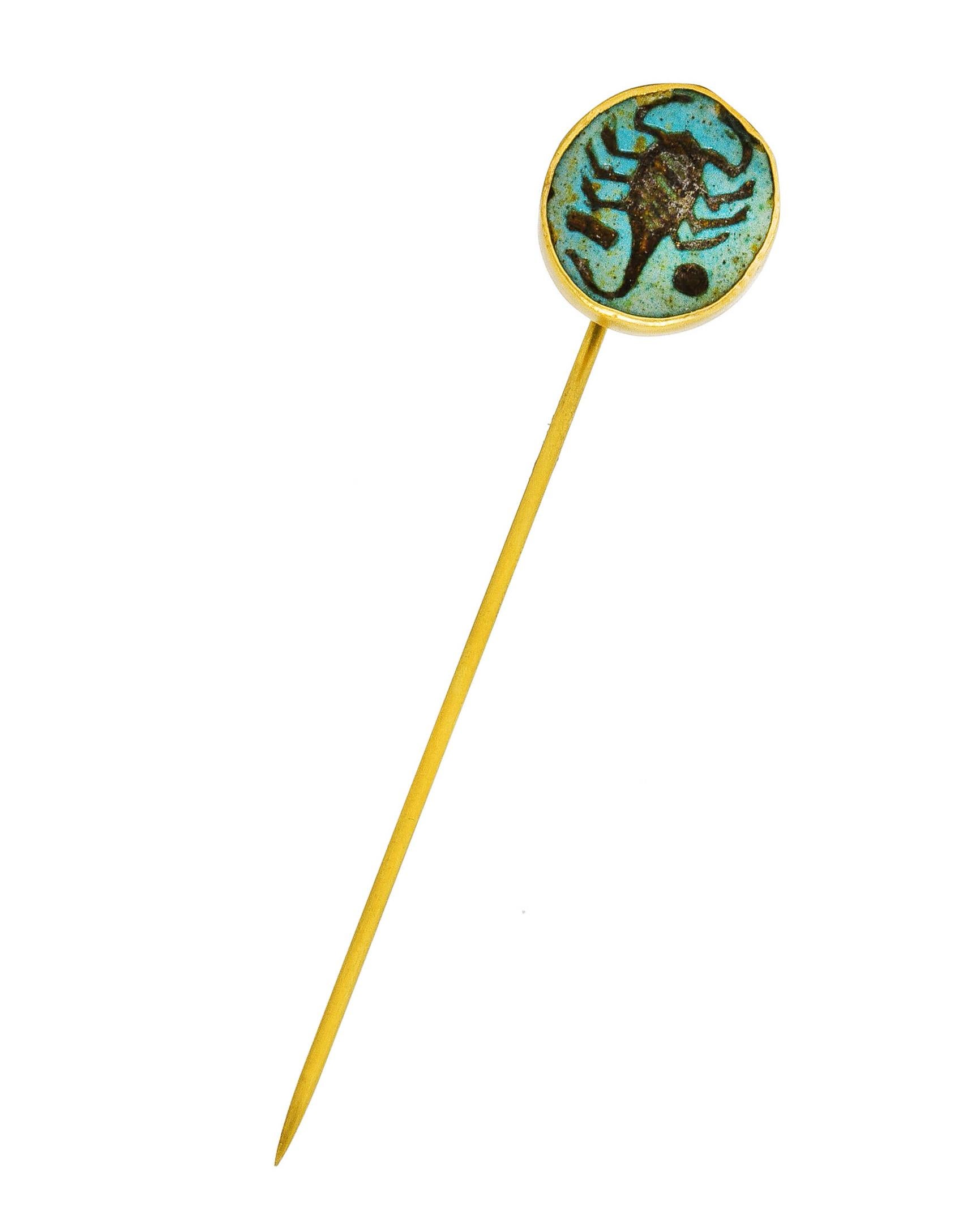 Centering an intaglio carved turquoise cabochon measuring approximately 13.0 mm in diameter. Opaque greenish-blue with brownish matrix - depicting a scorpion with geometric symbols. Bezel set in a grooved swirling bezel cup. Completed by stick pin.