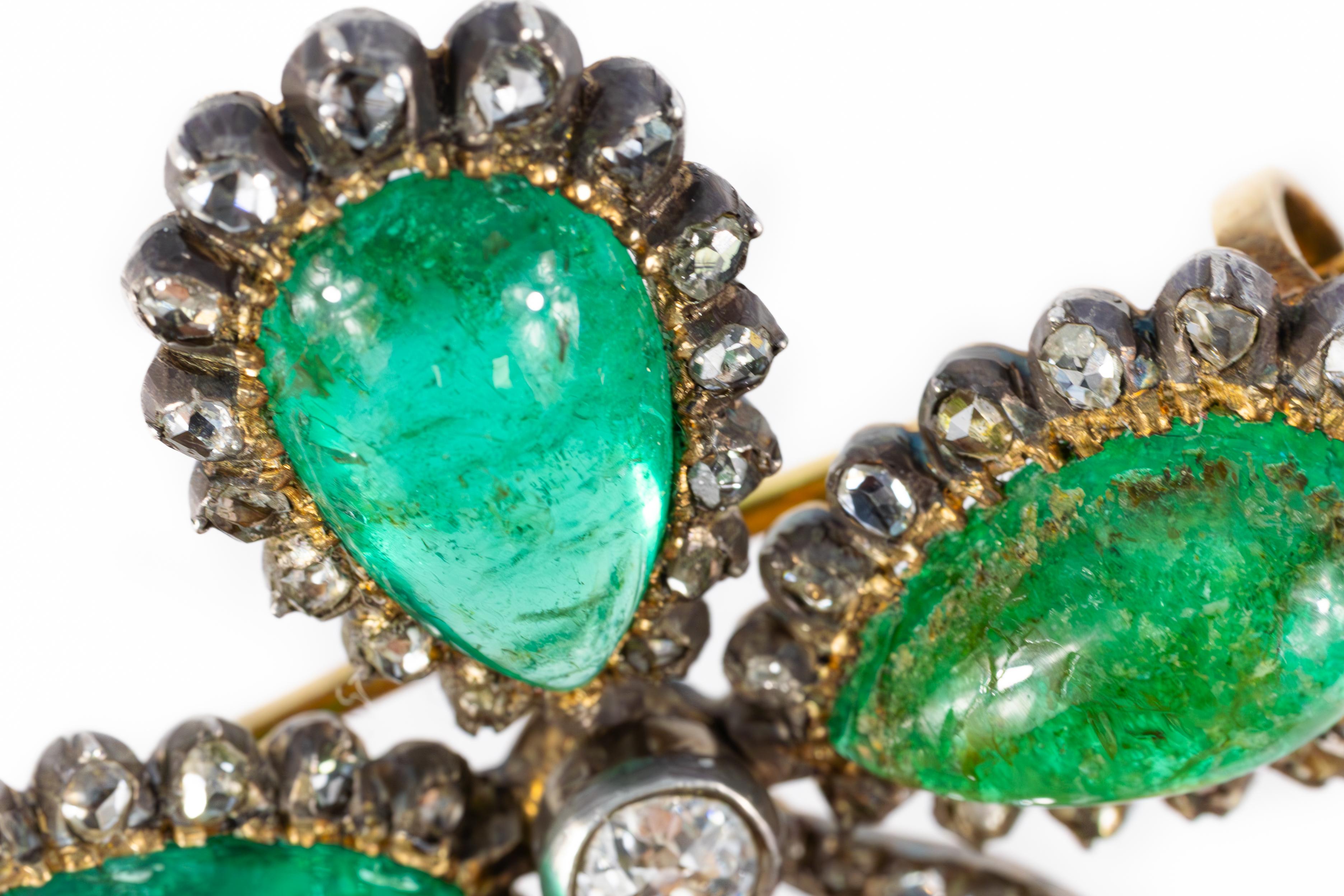 Cette broche de l'époque victorienne est un magnifique exemple d'artisanat ancien. Conçue comme un trèfle à quatre feuilles, elle est ornée de quatre émeraudes cabochons en forme de poire, dont les teintes vertes profondes sont rehaussées par un