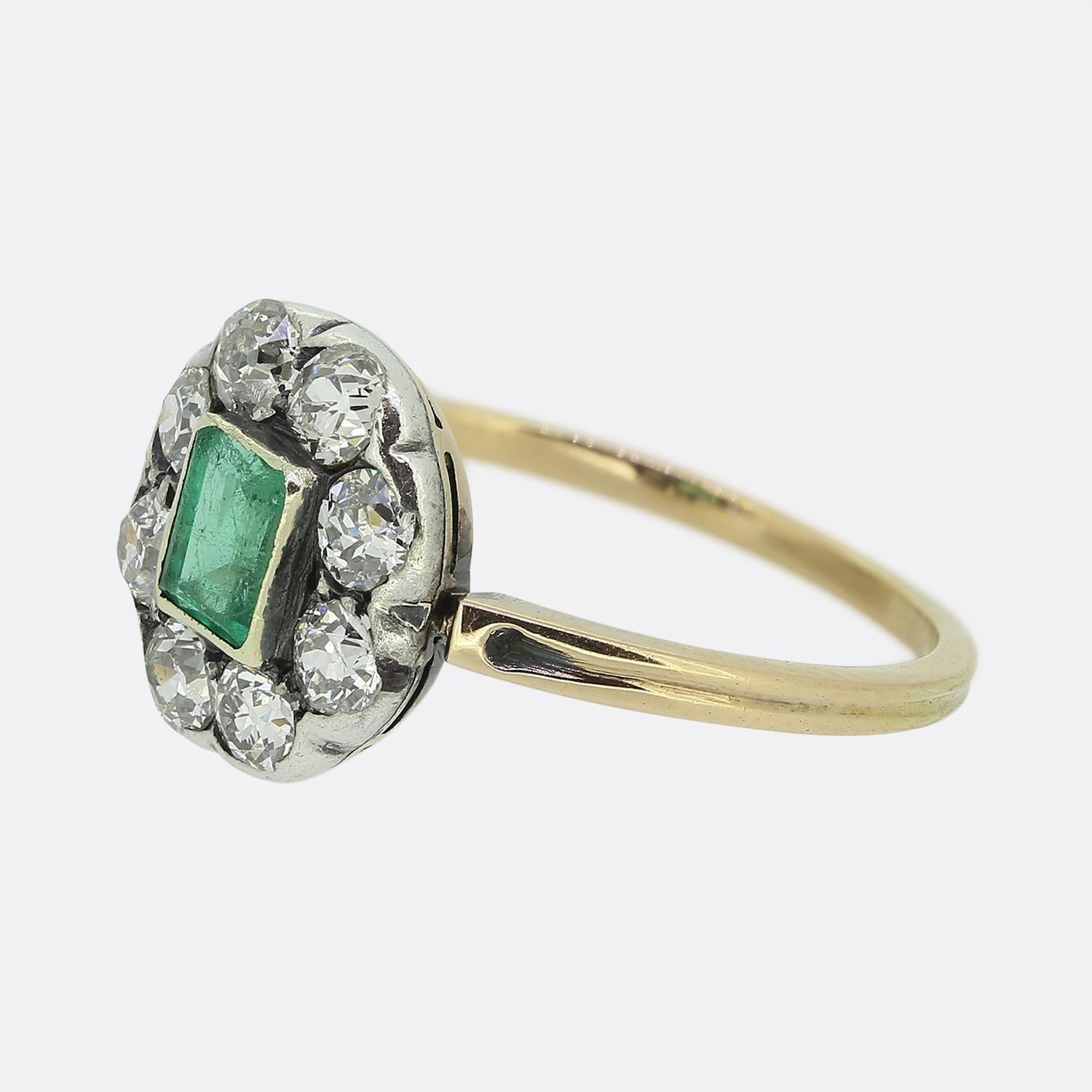 Here we a wonderful emerald and diamond cluster ring dating back to the Victorian period. This antique piece showcases a single emerald cut natural emerald which sits slightly risen at the centre of the face in a bezel style setting. This principal