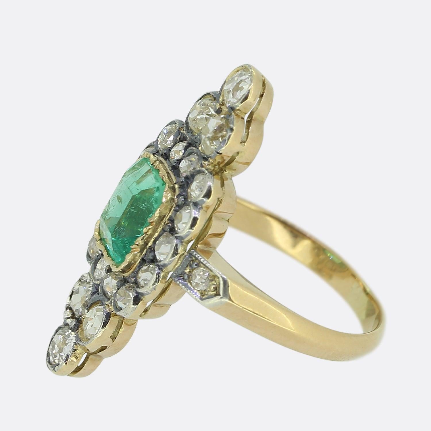 Here we have a classic navette ring dating back to the Victorian period. This antique piece showcases a single rectangular cushion cut emerald at the centre of the face surrounded by a vast silver set backdrop of round faceted old cut diamonds. Each